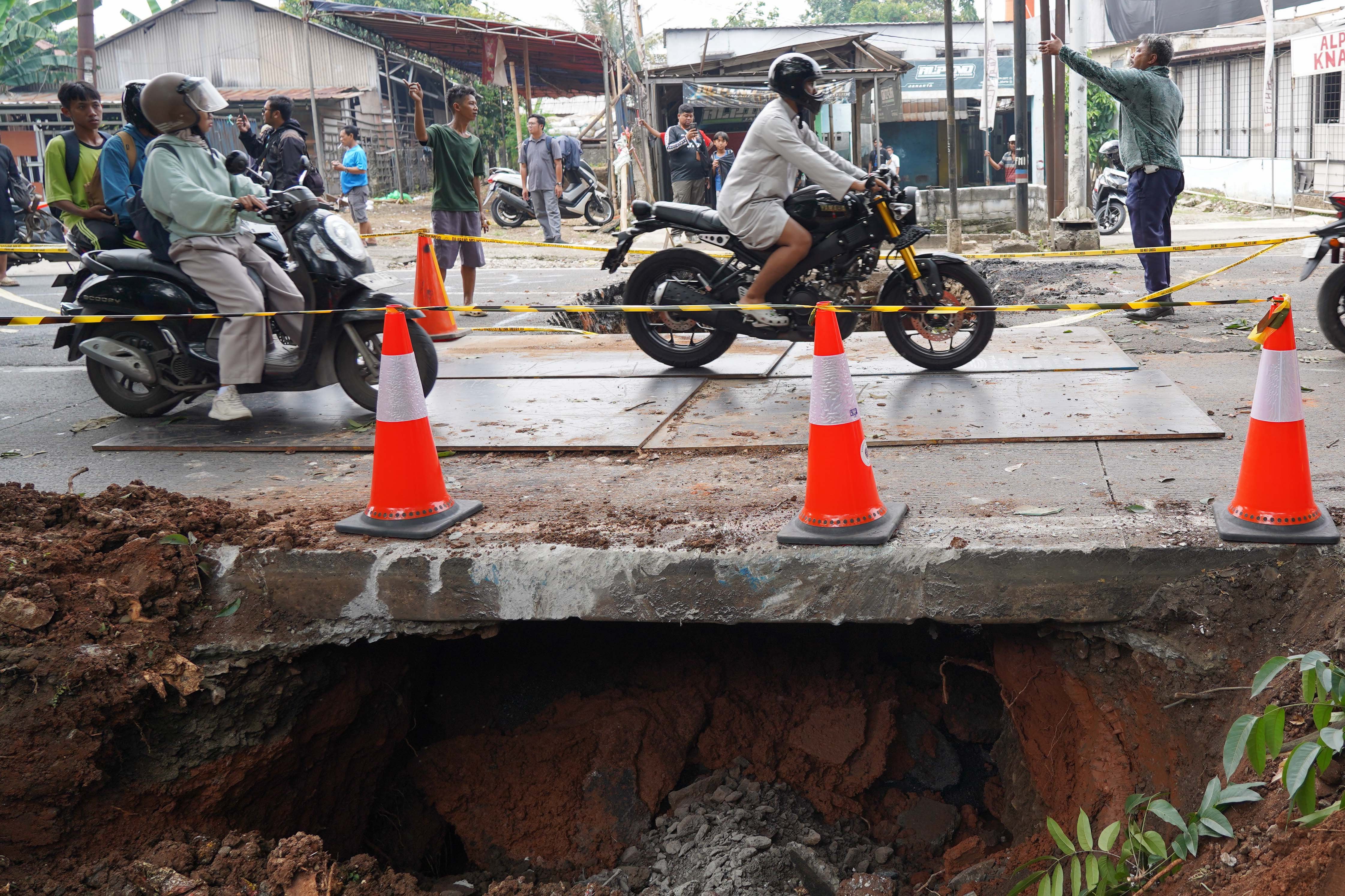 Pengendara sepeda motor melintas di dekat lubang dari amblasnya Jalan Raya Lenteng Agung, Jagakarsa, Jakarta Selatan, Jumat (29/5/2026). Akibat jalan tersebut amblas sedalam tiga meter dengan lebar empat meter ini membuat arus lalu lintas dari arah Jakarta menuju Depok mengalami kemacetan.