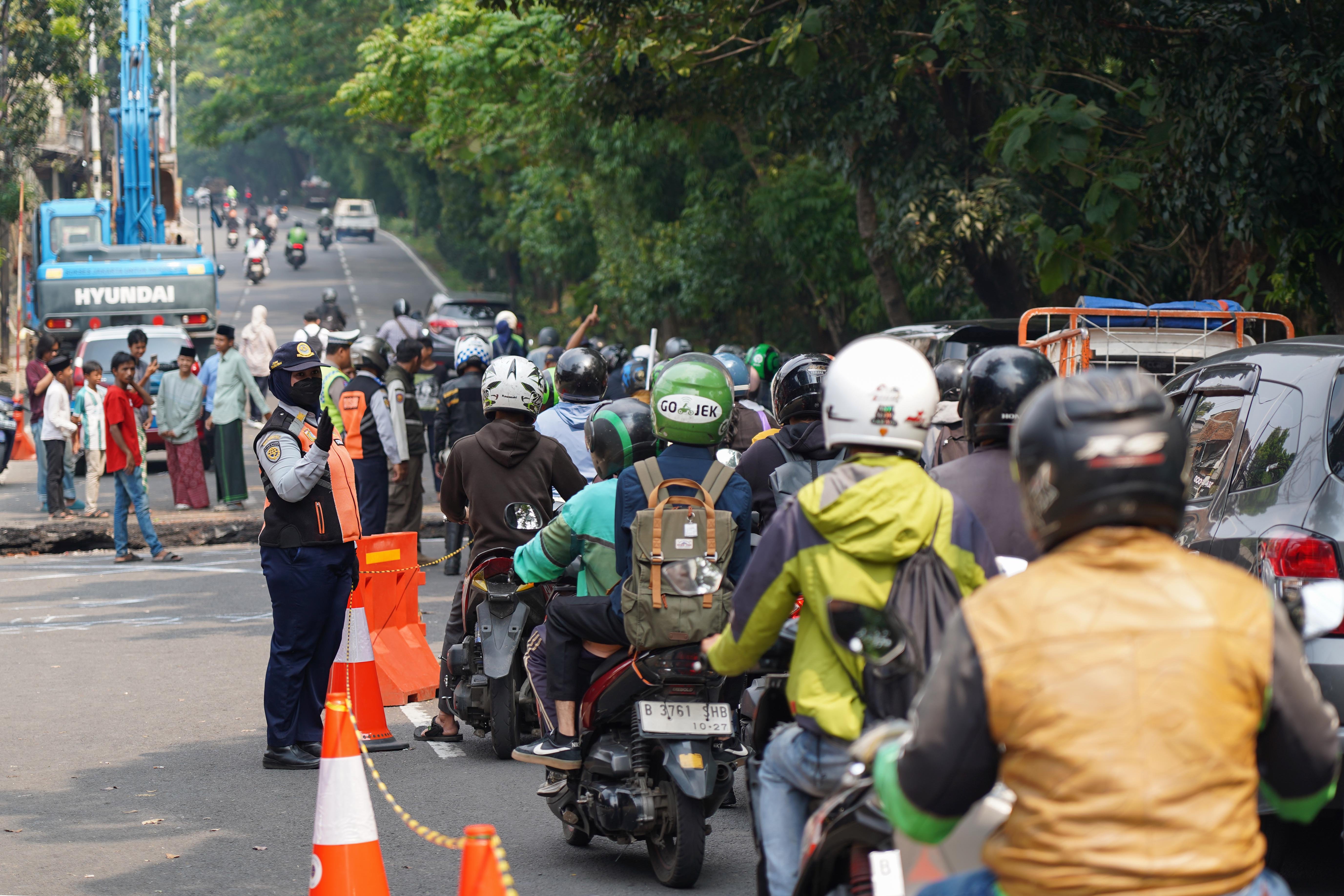 Petugas Dinas Perhubungan mengatur pengendara saat amblasnya Jalan Raya Lenteng Agung, Jagakarsa, Jakarta Selatan, Jumat (29/5/2026). Akibat jalan tersebut amblas sedalam tiga meter dengan lebar empat meter ini membuat arus lalu lintas dari arah Jakarta menuju Depok mengalami kemacetan.