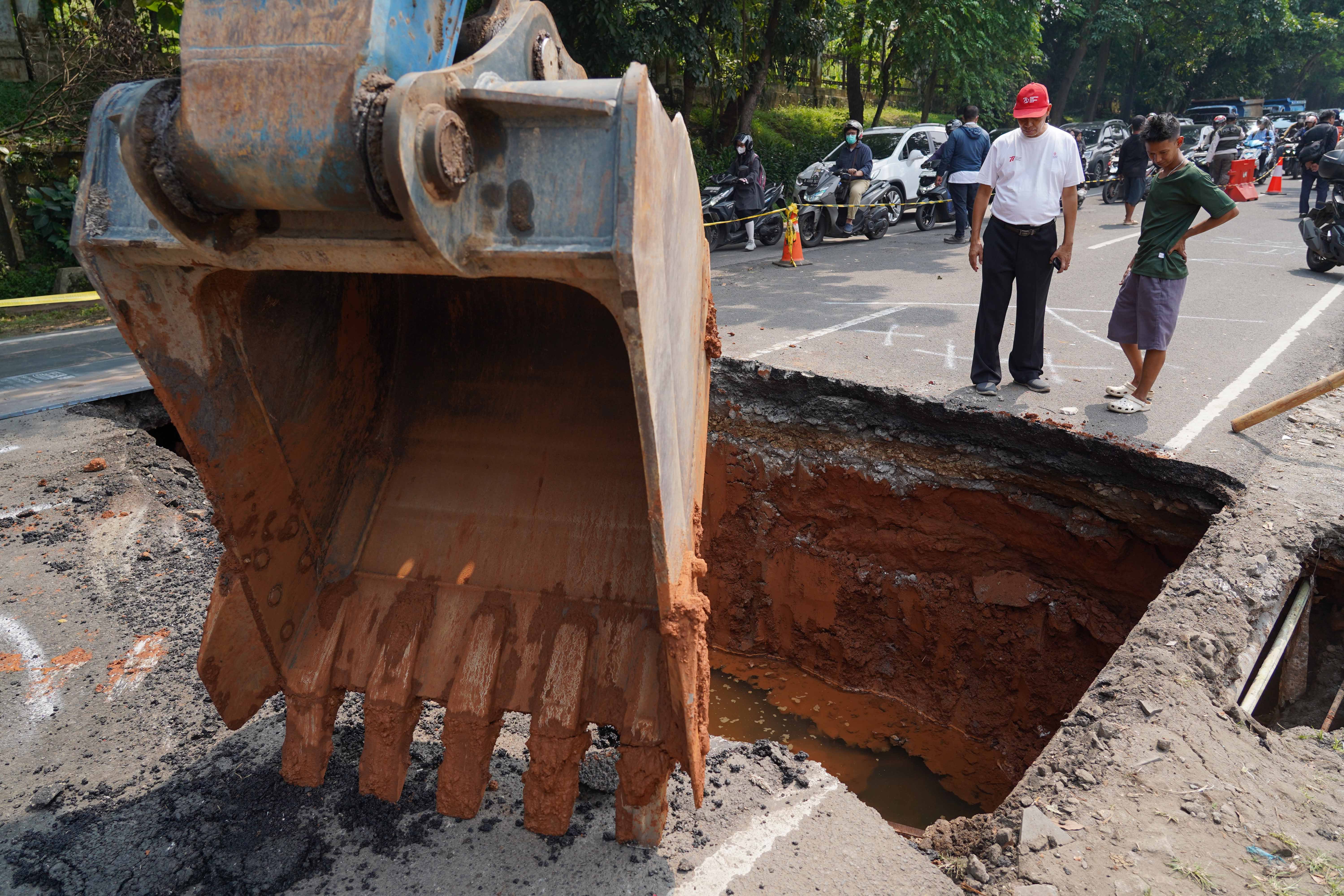 Warga melihat lubang dari amblasnya Jalan Raya Lenteng Agung, Jagakarsa, Jakarta Selatan, Jumat (29/5/2026). Akibat jalan tersebut amblas sedalam tiga meter dengan lebar empat meter ini membuat arus lalu lintas dari arah Jakarta menuju Depok mengalami kemacetan.