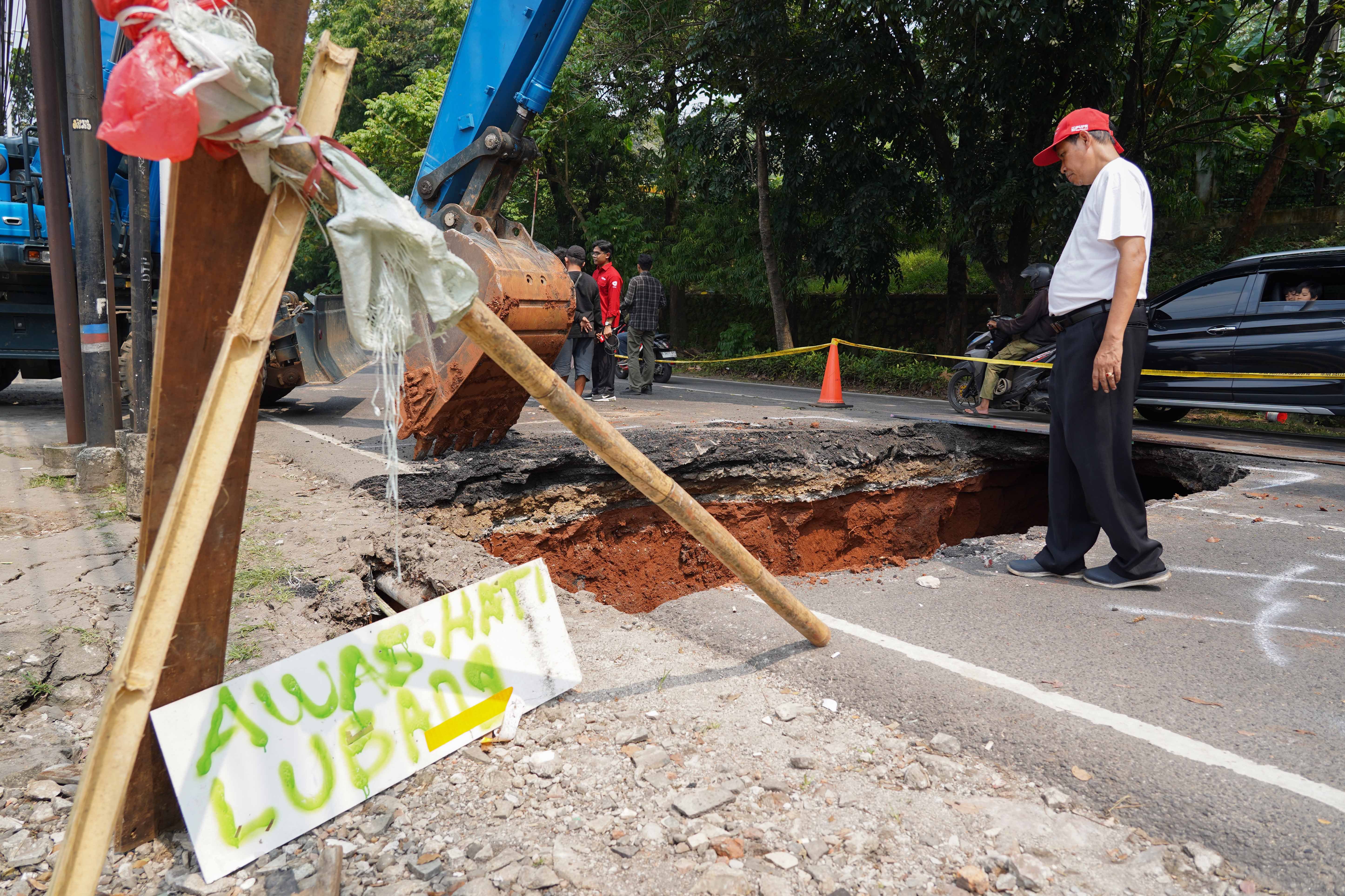 Warga melihat lubang dari amblasnya Jalan Raya Lenteng Agung, Jagakarsa, Jakarta Selatan, Jumat (29/5/2026). Akibat jalan tersebut amblas sedalam tiga meter dengan lebar empat meter ini membuat arus lalu lintas dari arah Jakarta menuju Depok mengalami kemacetan.