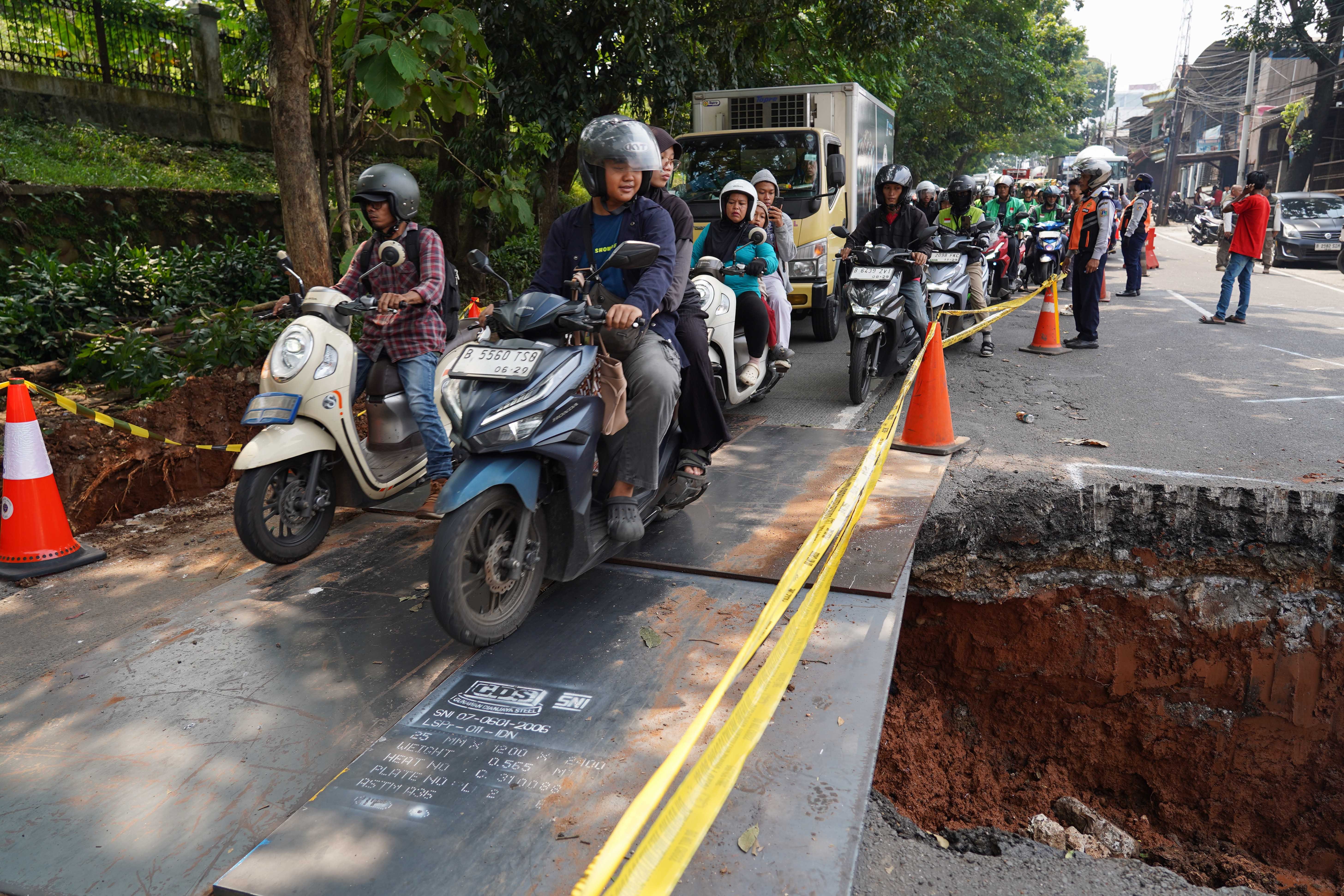 Pengendara melintas di dekat lubang dari amblasnya Jalan Raya Lenteng Agung, Jagakarsa, Jakarta Selatan, Jumat (29/5/2026). Akibat jalan tersebut amblas sedalam tiga meter dengan lebar empat meter ini membuat arus lalu lintas dari arah Jakarta menuju Depok mengalami kemacetan.