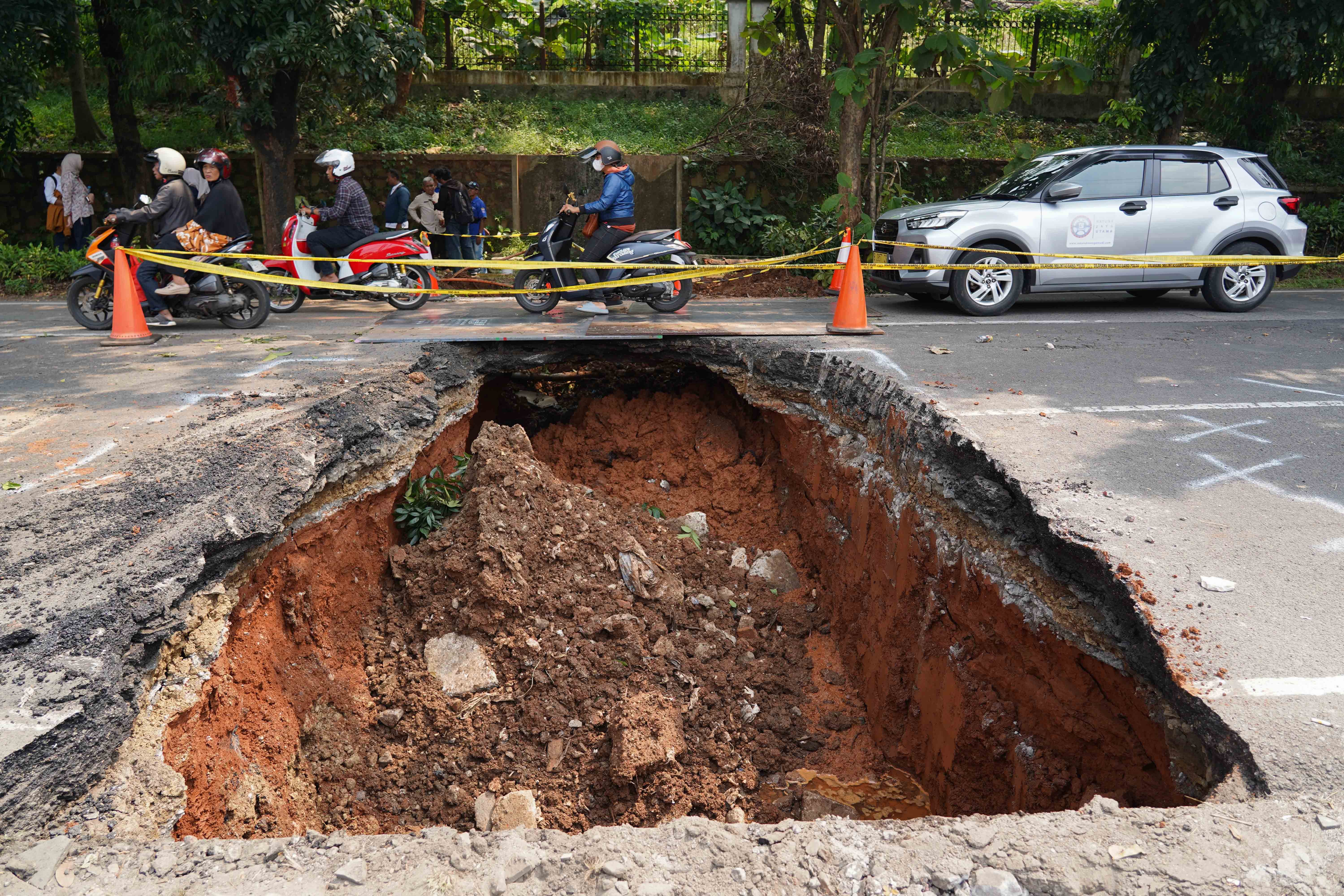 Pengendara melintas di dekat lubang dari amblasnya Jalan Raya Lenteng Agung, Jagakarsa, Jakarta Selatan, Jumat (29/5/2026). Akibat jalan tersebut amblas sedalam tiga meter dengan lebar empat meter ini membuat arus lalu lintas dari arah Jakarta menuju Depok mengalami kemacetan.