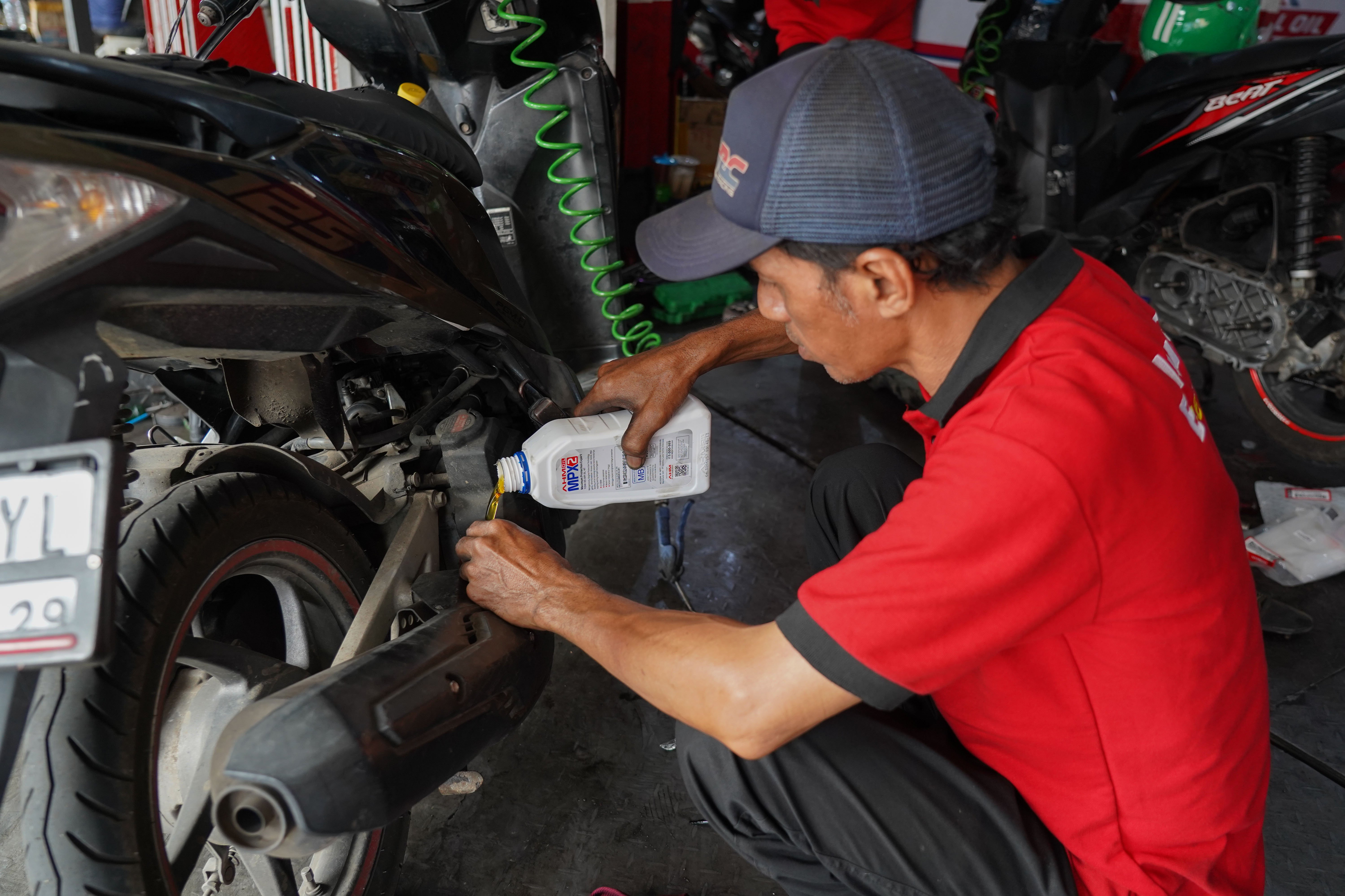 Mekanik menuangkan oli sepeda motor di salah satu bengkel di kawasan Pasar Minggu, Jakarta, Selasa (9/6/2026). Melemahnya nilai tukar rupiah terhadap dolar Amerika membuat harga onderdil motor seperti oli, ban hingga kampas rem mengalami kenaikan harga rata-rata dari Rp 15 ribu hingga Rp 20 ribu.