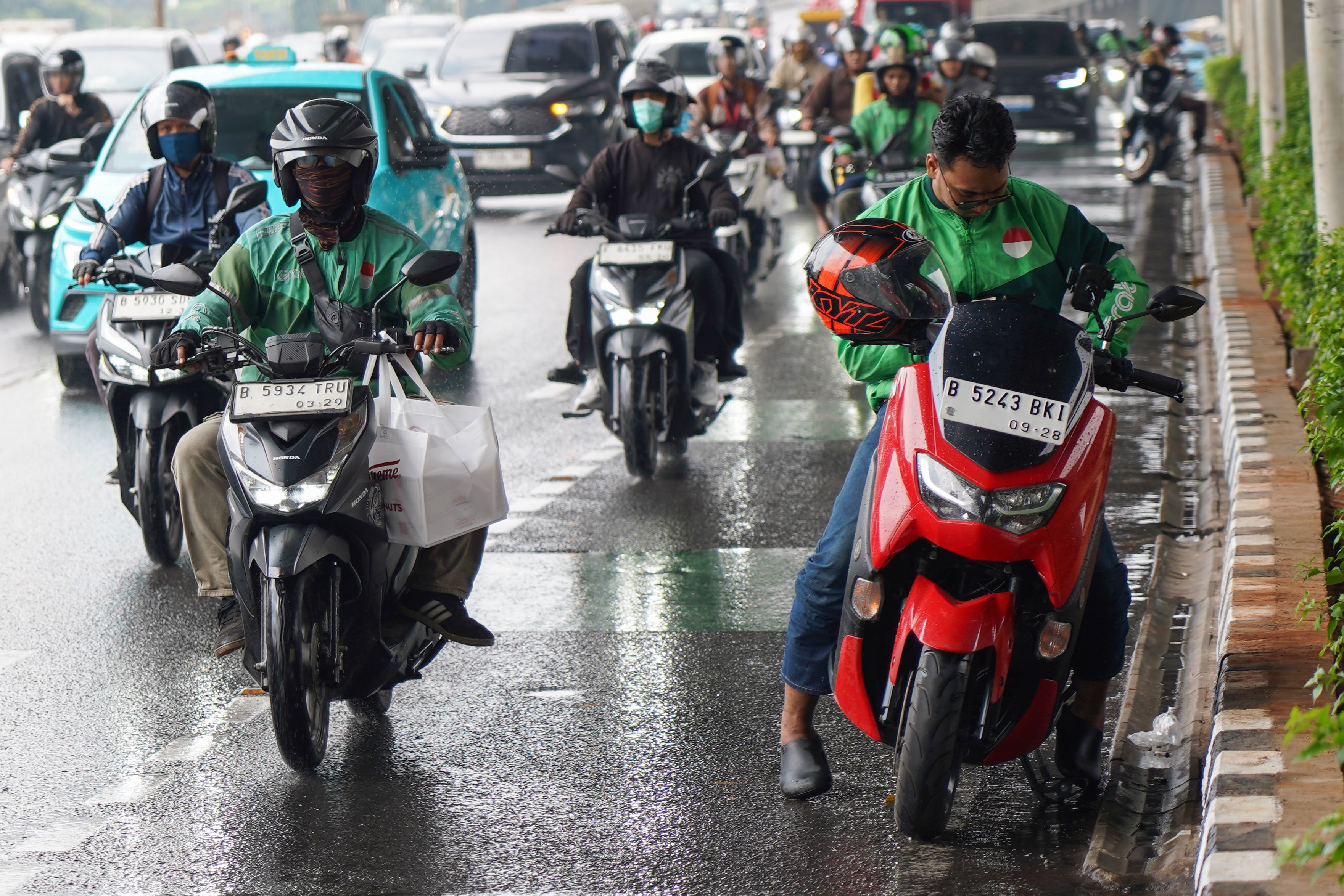 Pengemudi ojek online atau ojol melintas di Jalan Gatot Subroto, Pancoran, Jakarta, Kamis (25/6/2026). Dua aplikator transportasi daring, Grab dan Gojek secara resmi telah menyatakan akan menerapkan potongan komisi 8% kepada mitra pengemudi transportasi roda dua mulai 1 Juli 2026 yang sesuai Peraturan Presiden (Perpres) Nomor 27 Tahun 2026 tentang Perlindungan Pekerja Transportasi Online.