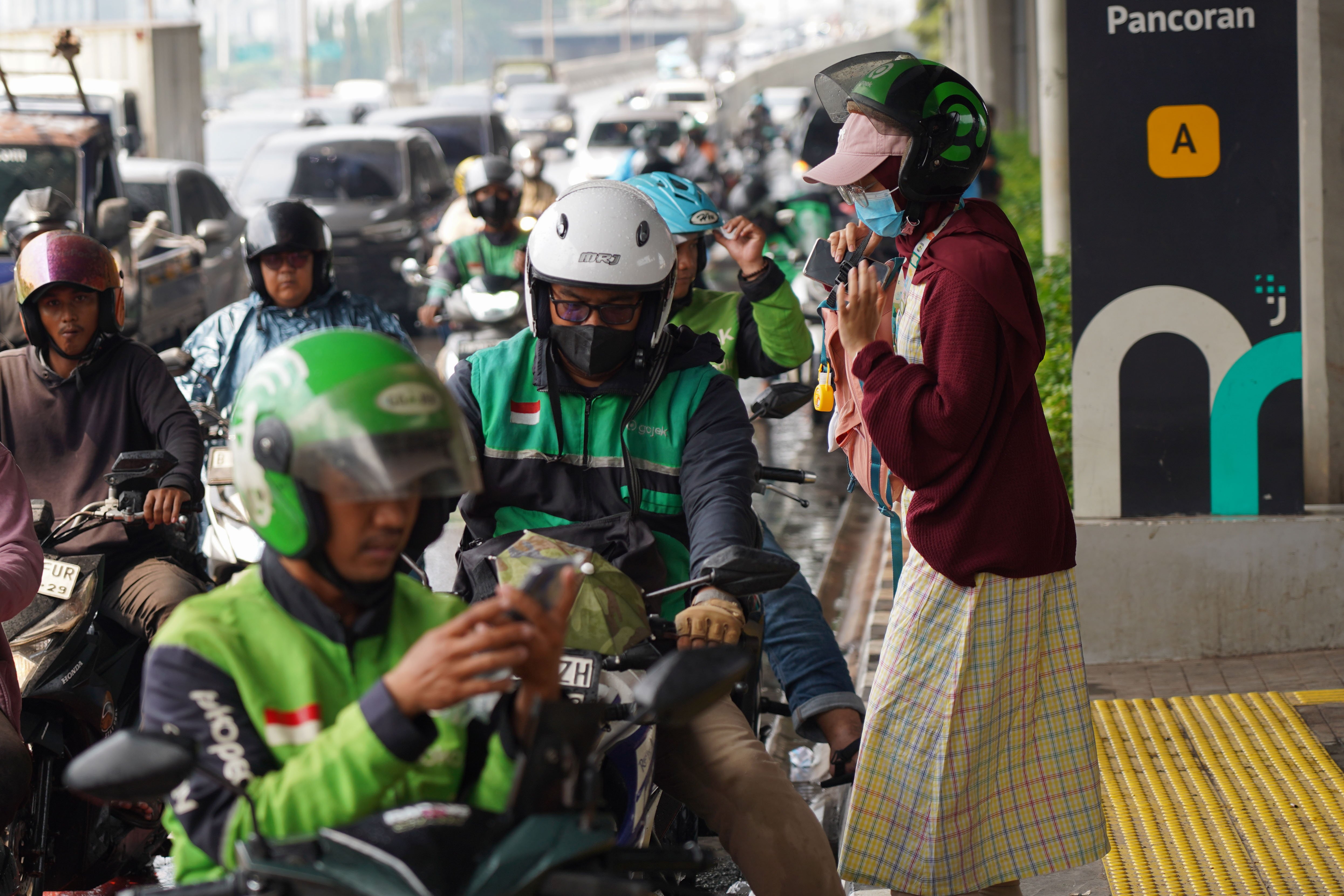 Pengemudi ojek online atau ojol membawa penumpang di Jalan Gatot Subroto, Pancoran, Jakarta, Kamis (25/6/2026). Dua aplikator transportasi daring, Grab dan Gojek secara resmi telah menyatakan akan menerapkan potongan komisi 8% kepada mitra pengemudi transportasi roda dua mulai 1 Juli 2026 yang sesuai Peraturan Presiden (Perpres) Nomor 27 Tahun 2026 tentang Perlindungan Pekerja Transportasi Online.