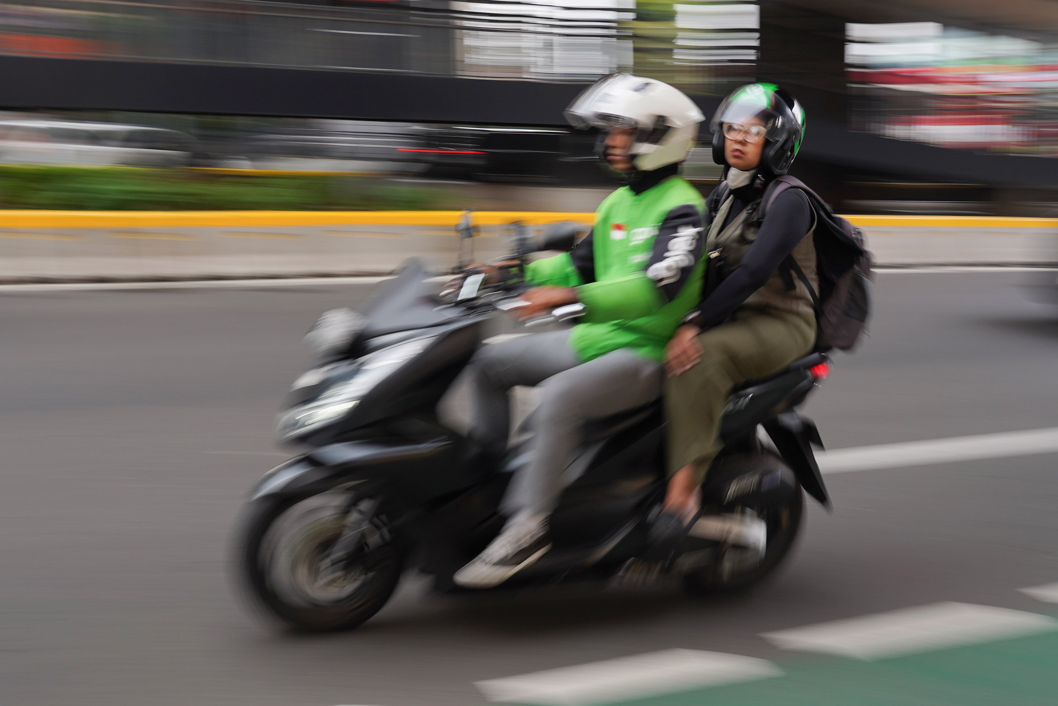 Pengemudi ojek online atau ojol membawa penumpang di Jalan HR Rasuna Said, Kuningan, Jakarta, Kamis (25/6/2026). Dua aplikator transportasi daring, Grab dan Gojek secara resmi telah menyatakan akan menerapkan potongan komisi 8% kepada mitra pengemudi transportasi roda dua mulai 1 Juli 2026 yang sesuai Peraturan Presiden (Perpres) Nomor 27 Tahun 2026 tentang Perlindungan Pekerja Transportasi Online.