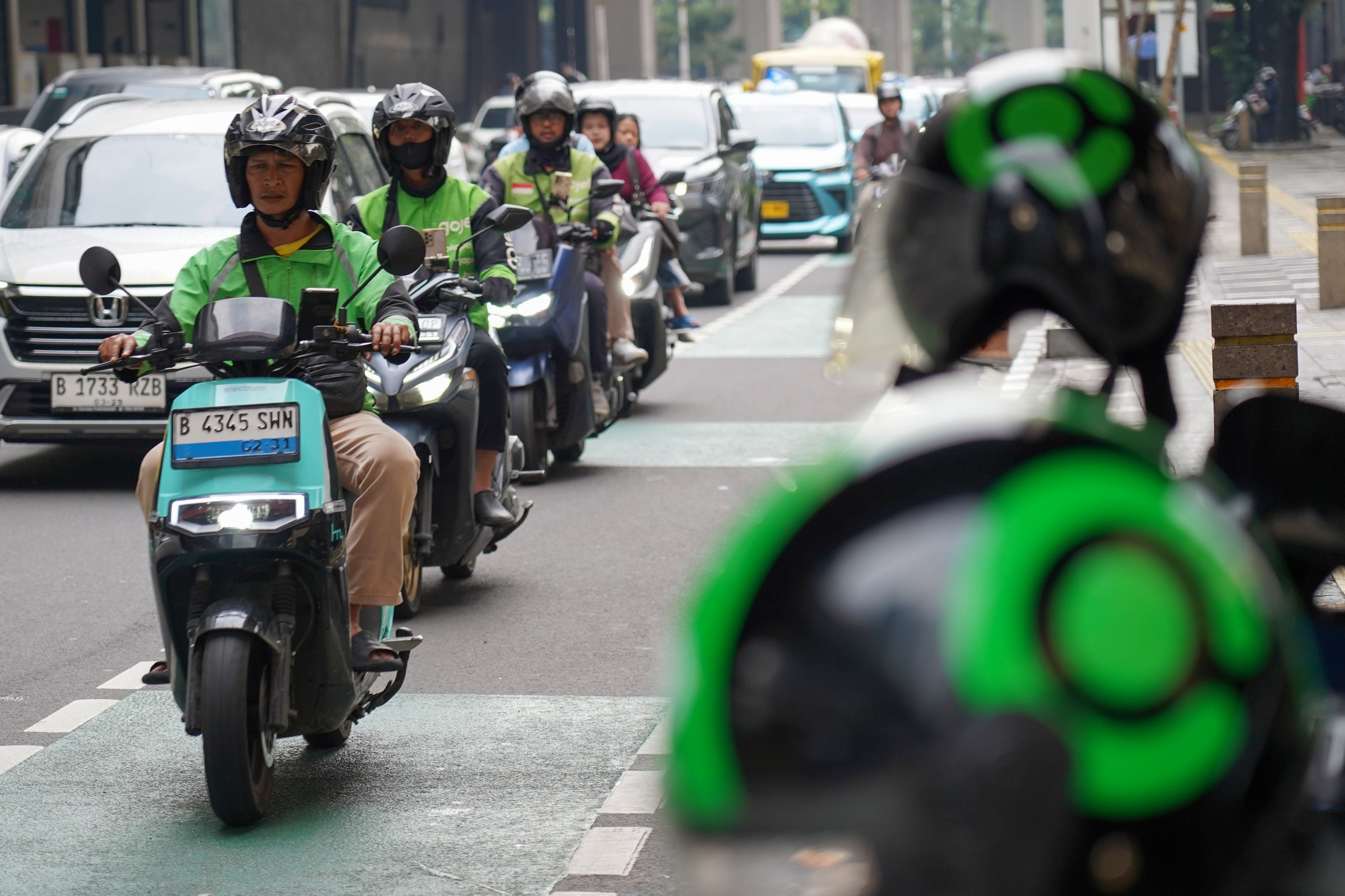 Pengemudi ojek online atau ojol melintas di Jalan HR Rasuna Said, Kuningan, Jakarta, Kamis (25/6/2026). Dua aplikator transportasi daring, Grab dan Gojek secara resmi telah menyatakan akan menerapkan potongan komisi 8% kepada mitra pengemudi transportasi roda dua mulai 1 Juli 2026 yang sesuai Peraturan Presiden (Perpres) Nomor 27 Tahun 2026 tentang Perlindungan Pekerja Transportasi Online.