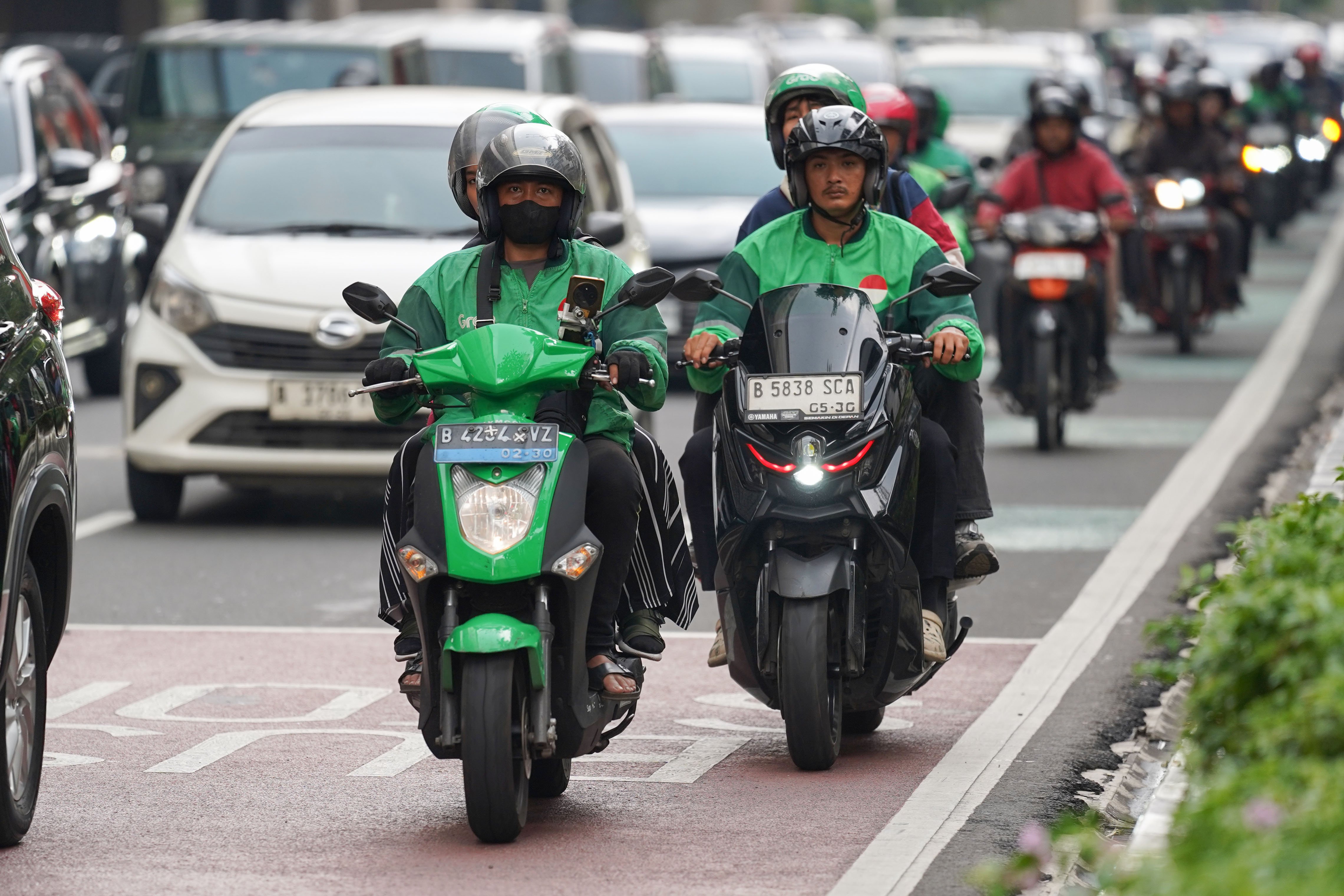 Pengemudi ojek online atau ojol membawa penumpang di Jalan HR Rasuna Said, Kuningan, Jakarta, Kamis (25/6/2026). Dua aplikator transportasi daring, Grab dan Gojek secara resmi telah menyatakan akan menerapkan potongan komisi 8% kepada mitra pengemudi transportasi roda dua mulai 1 Juli 2026 yang sesuai Peraturan Presiden (Perpres) Nomor 27 Tahun 2026 tentang Perlindungan Pekerja Transportasi Online.