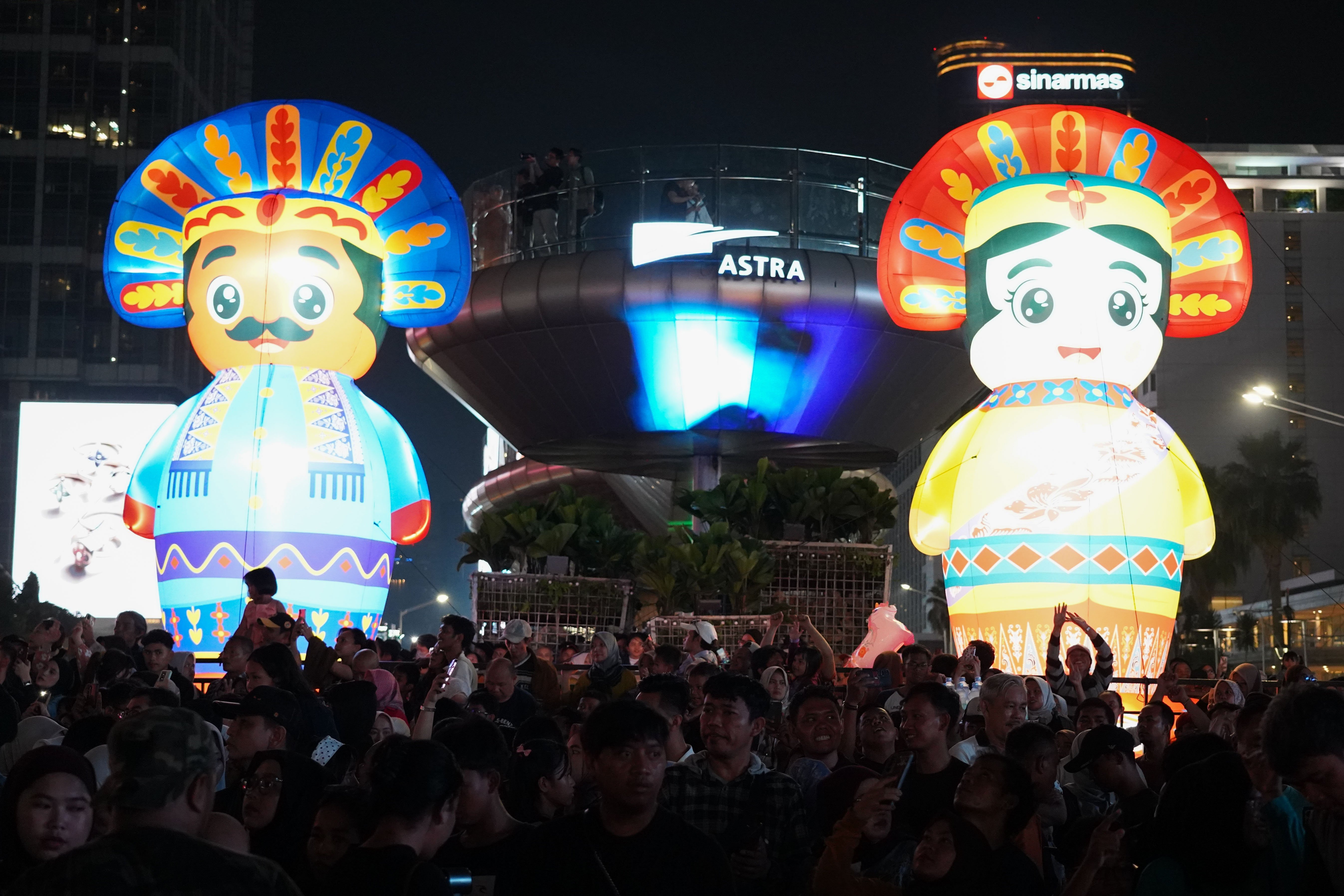 Warga menyaksikan pertunjukkan musik pada malam puncak HUT ke-499 Kota Jakarta di kawasan Bundaran HI, Sabtu (27/6/2026). Acara tersebut dimeriahkan berbagai pertunjukkan mulai dari video mapping, instalasi seni, atraksi pencahayaan hingga panggung hiburan yang menampilkan konser musik dari musisi papan atas.