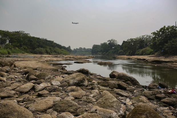 Sebuah pesawat melintas di atas Sungai Cisadane yang mulai mengering di Tangerang, Banten, Rabu (15/7/20236). Debit air Sungai Cisadane menurun akibat tidak turunnya hujan di wilayah Tangerang dan Bogor selama sekitar satu bulan terakhir sehingga menyebabkan sungai mengalami kekeringan.