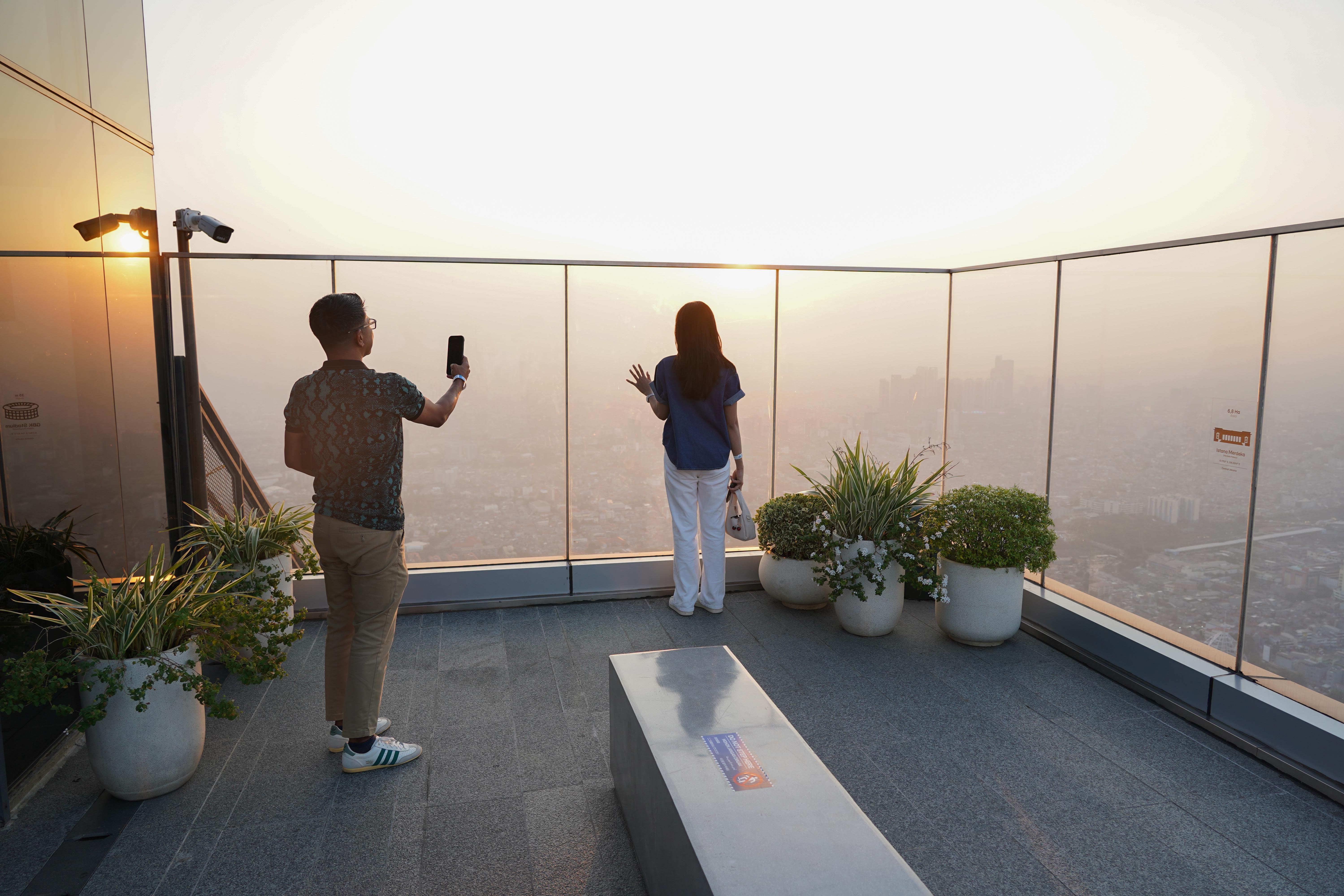 Warga berfoto saat berkunjung ke Sky Garden UP at Thamrin Nine di Autograph Tower, Jakarta Pusat, Rabu (15/7/2026). Objek wisata tersebut menawarkan tempat untuk menikmati suasana panorama Kota Jakarta dari atas gedung tertinggi di Indonesia dengan ketinggian 385 meter.