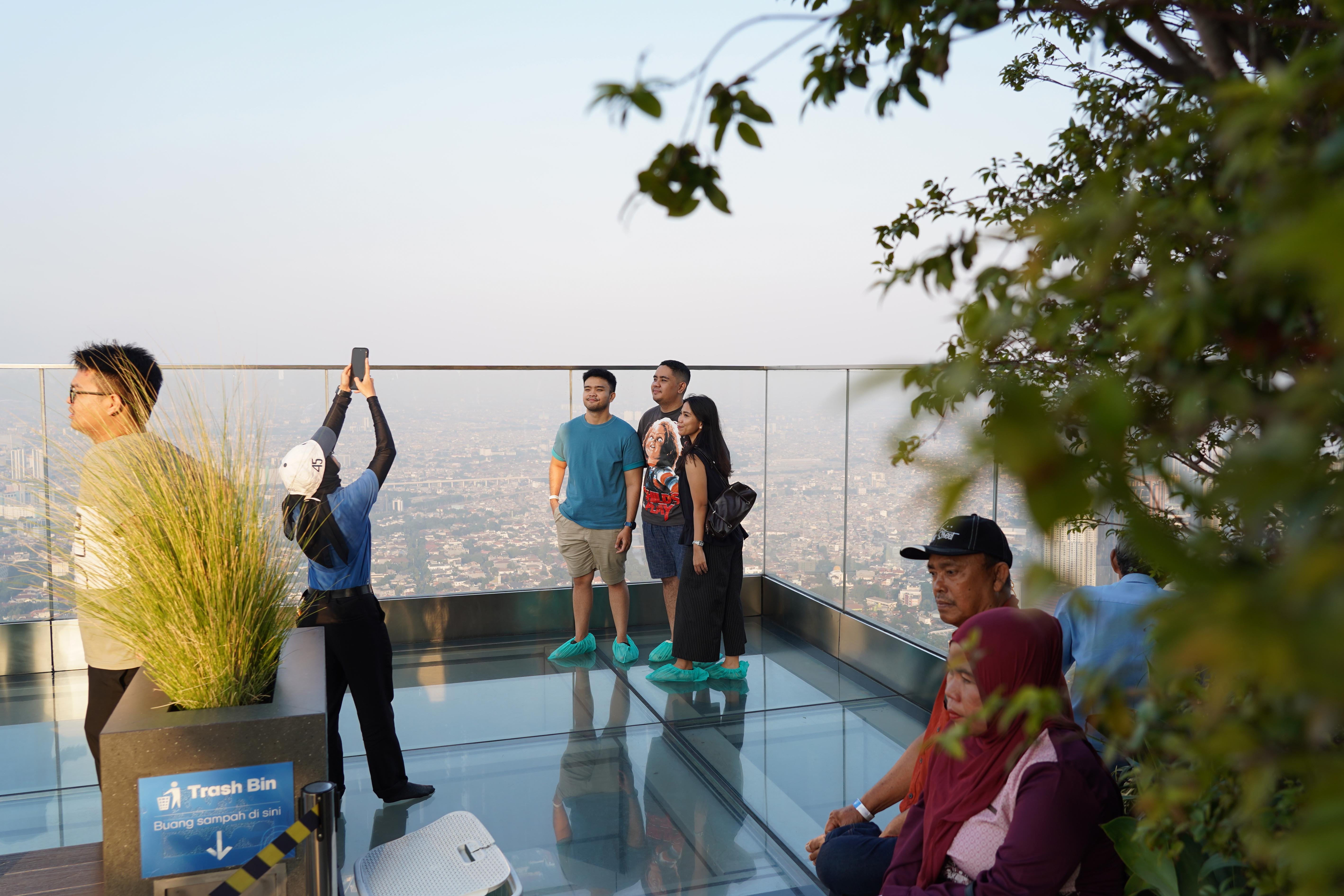 Warga berfoto saat berkunjung ke Sky Garden UP at Thamrin Nine di Autograph Tower, Jakarta Pusat, Rabu (15/7/2026). Objek wisata tersebut menawarkan tempat untuk menikmati suasana panorama Kota Jakarta dari atas gedung tertinggi di Indonesia dengan ketinggian 385 meter.