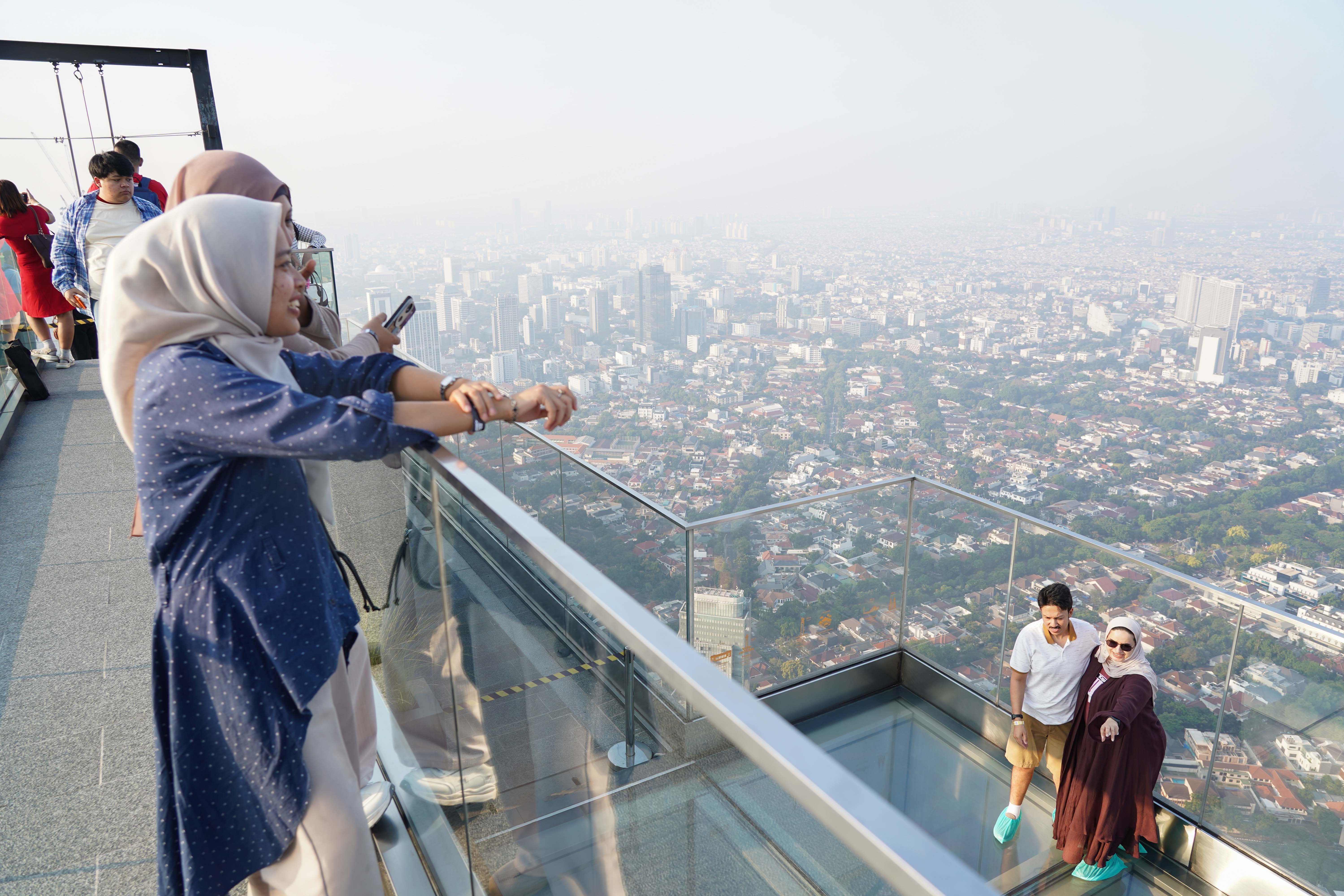 Warga melihat gedung bertingkat saat berkunjung ke Sky Garden UP at Thamrin Nine di Autograph Tower, Jakarta Pusat, Rabu (15/7/2026). Objek wisata tersebut menawarkan tempat untuk menikmati suasana panorama Kota Jakarta dari atas gedung tertinggi di Indonesia dengan ketinggian 385 meter.