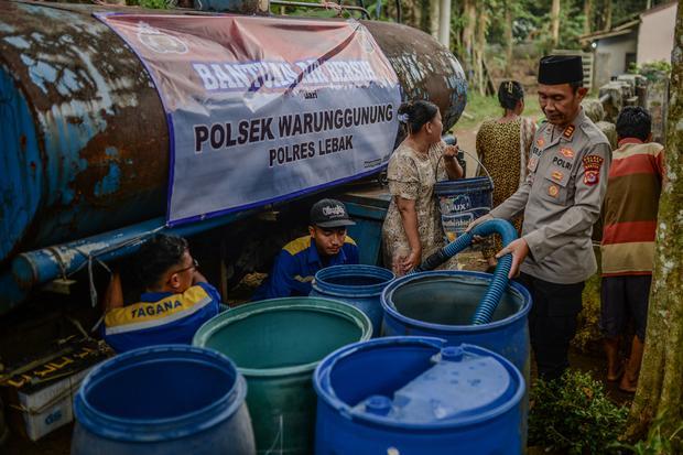 Polisi mengisi air bersih ke dalam drum milik warga di Desa Cibuah, Lebak, Banten, Senin (20/7/2026). Pemerintah Kabupaten Lebak telah menyalurkan sebanyak 40.000 liter air bersih dalam sepekan terakhir guna memenuhi kebutuhan sehari-hari warga yang terdampak kekeringan akibat musim kemarau di 11 titik di Lebak.