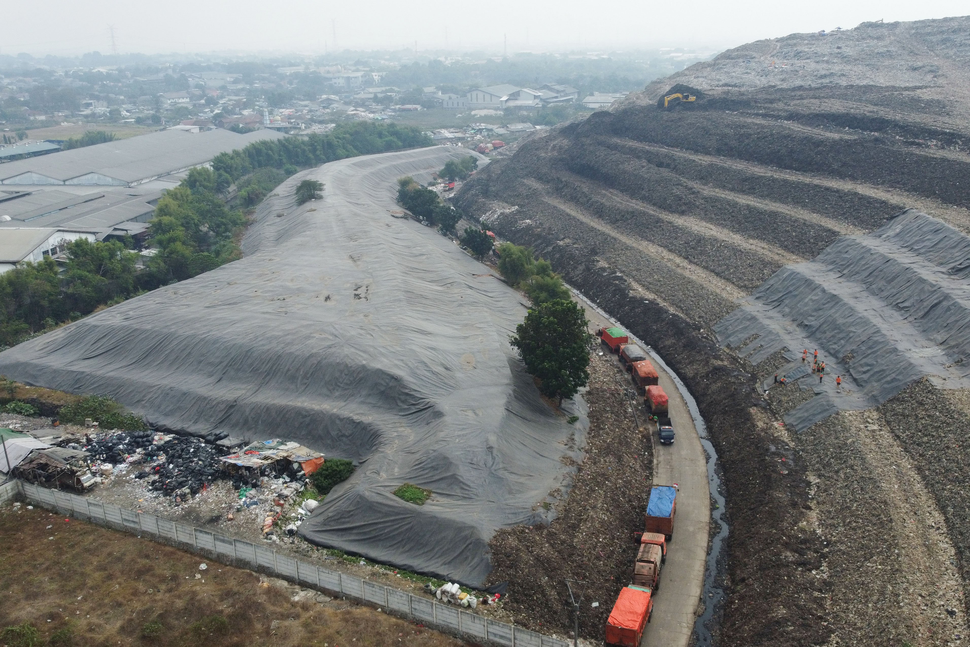 Foto udara sebagian tumpukan sampah yang telah ditutup geomembran di Tempat Pembuangan Sampah Terpadu (TPST) Bantargebang, Kota Bekasi, Jawa Barat, Selasa (4/8/2026). Pemasangan plastik kedap air tersebut merupakan transisi sistem pengolahan sampah dari praktik open dumping menuju controlled landfill yang ditargetkan sepenuhnya diterapkan pada 2029 untuk melindungi area timbunan dan mengurangi cemaran air lindi ke lingkungan.