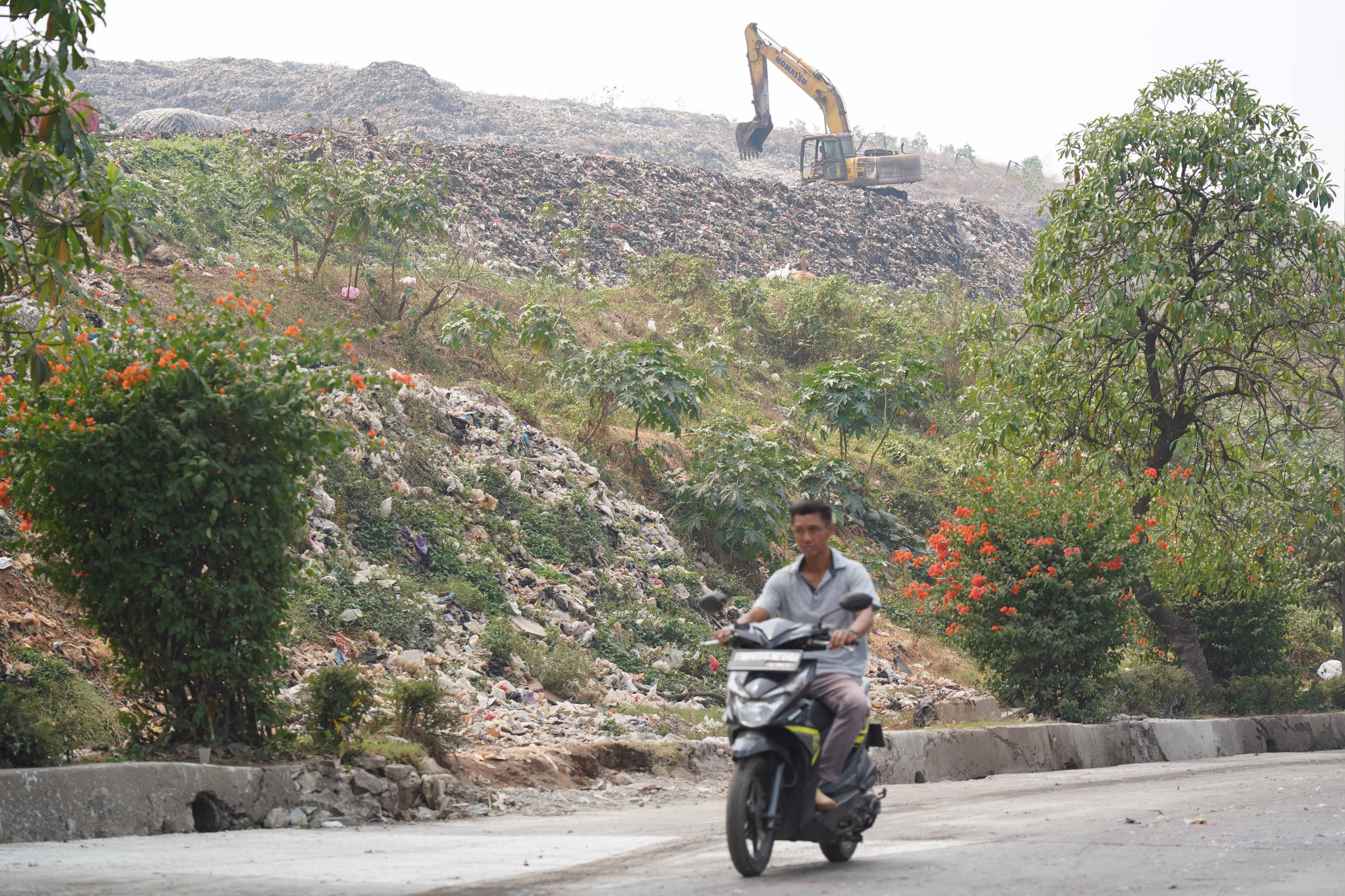 Warga yang mengendarai sepeda motor melintas di dekat tumpukan sampah di Tempat Pengolahan Sampah Terpadu (TPST) Bantargebang, Kota Bekasi, Jawa Barat, Selasa (4/8/2026). Pemprov DKI Jakarta tengah melakukan transisi sistem pengolahan sampah di TPST Bantargebang dari praktik open dumping menuju controlled landfill yang ditargetkan sepenuhnya diterapkan pada 2029.