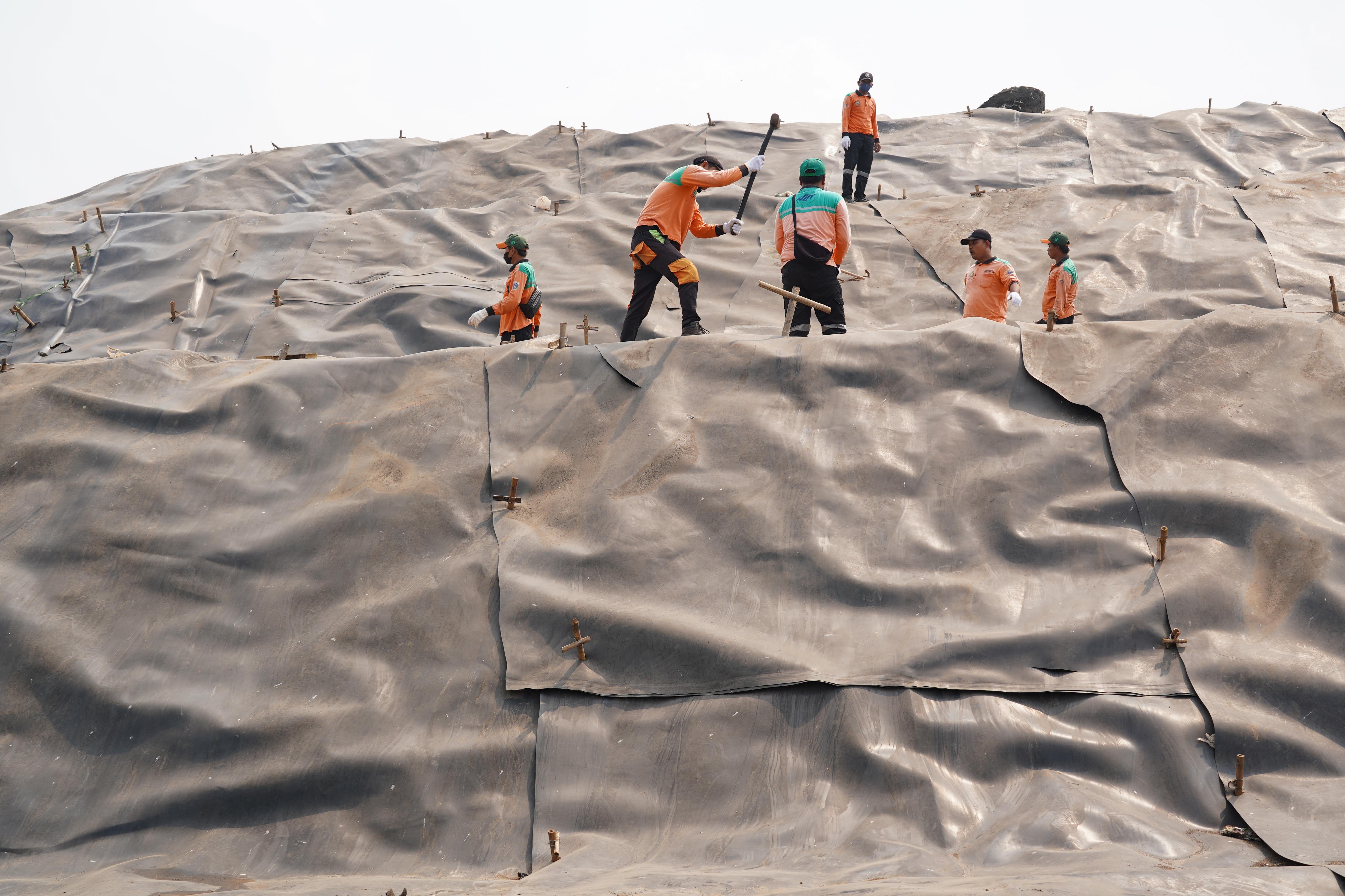 Petugas memasang geomembran untuk menutup tumpukan sampah di Tempat Pengolahan Sampah Terpadu (TPST) Bantargebang, Kota Bekasi, Jawa Barat, Selasa (4/8/2026). Pemasangan plastik kedap air tersebut merupakan transisi sistem pengolahan sampah dari praktik open dumping menuju controlled landfill yang ditargetkan sepenuhnya diterapkan pada 2029 untuk melindungi area timbunan dan mengurangi cemaran air lindi ke lingkungan.