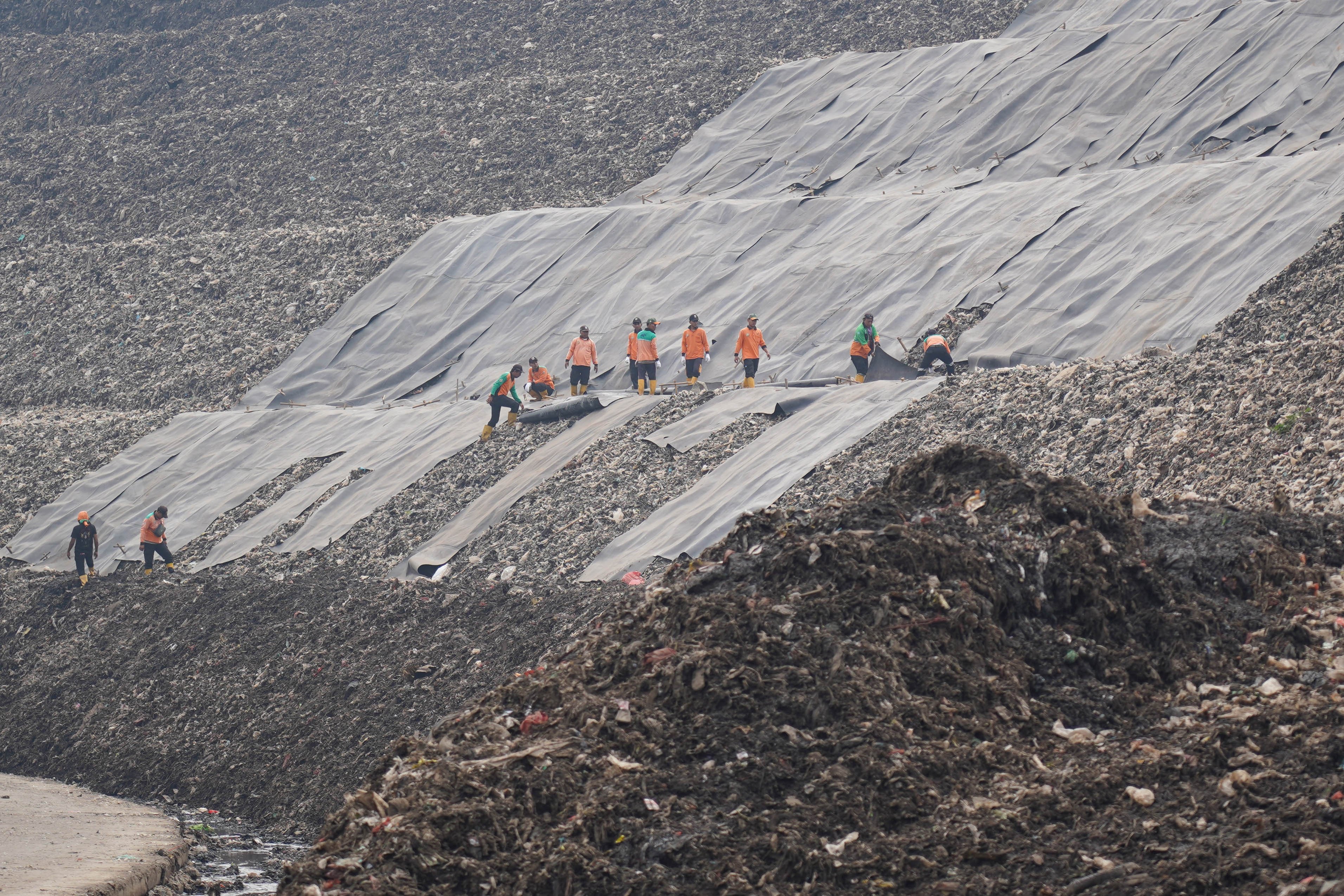 Petugas memasang geomembran untuk menutup tumpukan sampah di Tempat Pengolahan Sampah Terpadu (TPST) Bantargebang, Kota Bekasi, Jawa Barat, Selasa (4/8/2026). Pemasangan plastik kedap air tersebut merupakan transisi sistem pengolahan sampah dari praktik open dumping menuju controlled landfill yang ditargetkan sepenuhnya diterapkan pada 2029 untuk melindungi area timbunan dan mengurangi cemaran air lindi ke lingkungan.
