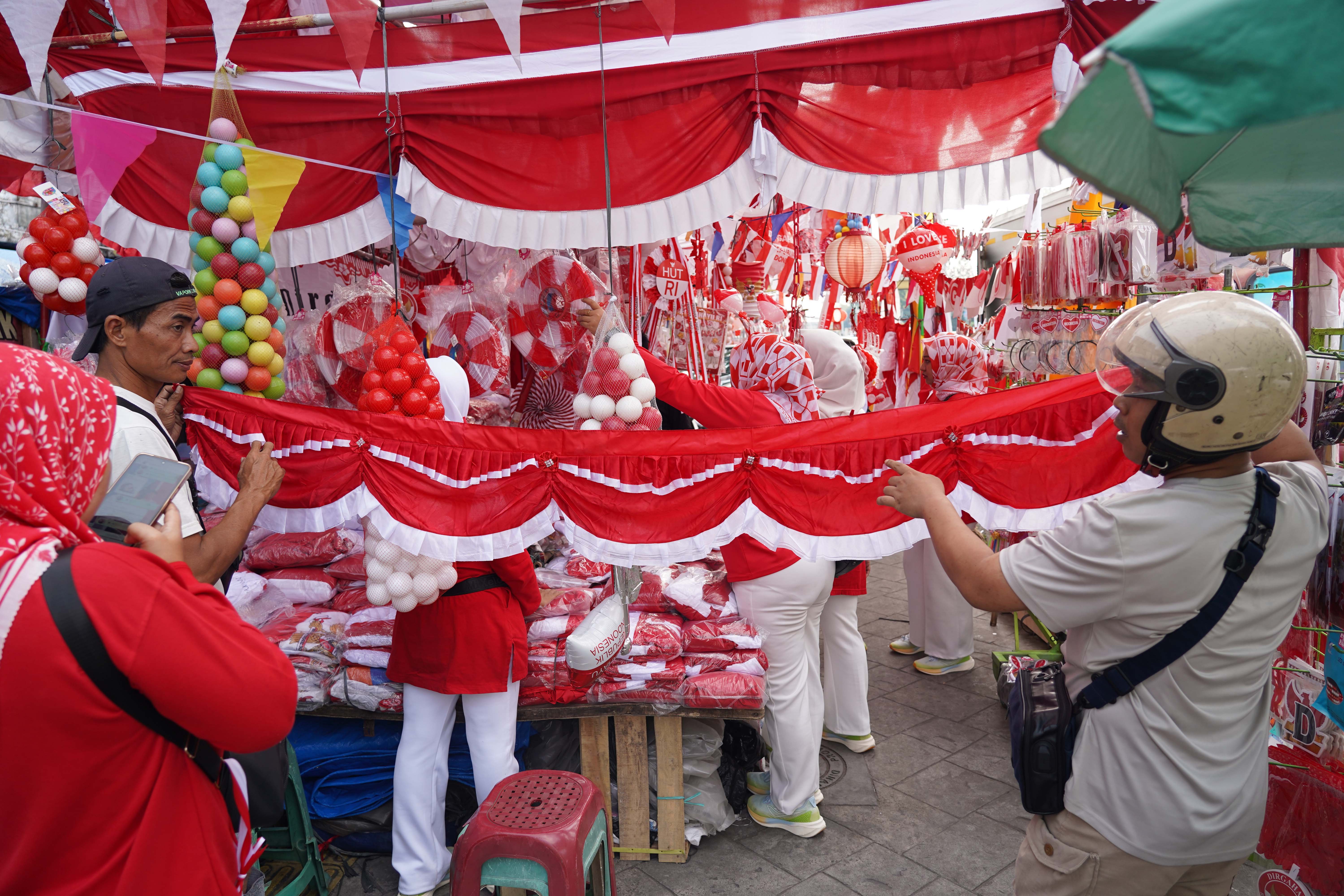 Pedagang melayani calon pembeli yang hendak membeli bendera merah putih yang dijualnya di Pasar Jatinegara, Jakarta Timur, Rabu (12/8/2026). Berdasarkan keterangan pedagang, menjelang Hari Ulang Tahun (HUT) Kemerdekaan Republik Indonesia ke-81 pada 17 Agustus 2026, penjualan aksesoris bernuansa merah putih meningkat dua kali lipat dibandingkan tahun lalu.