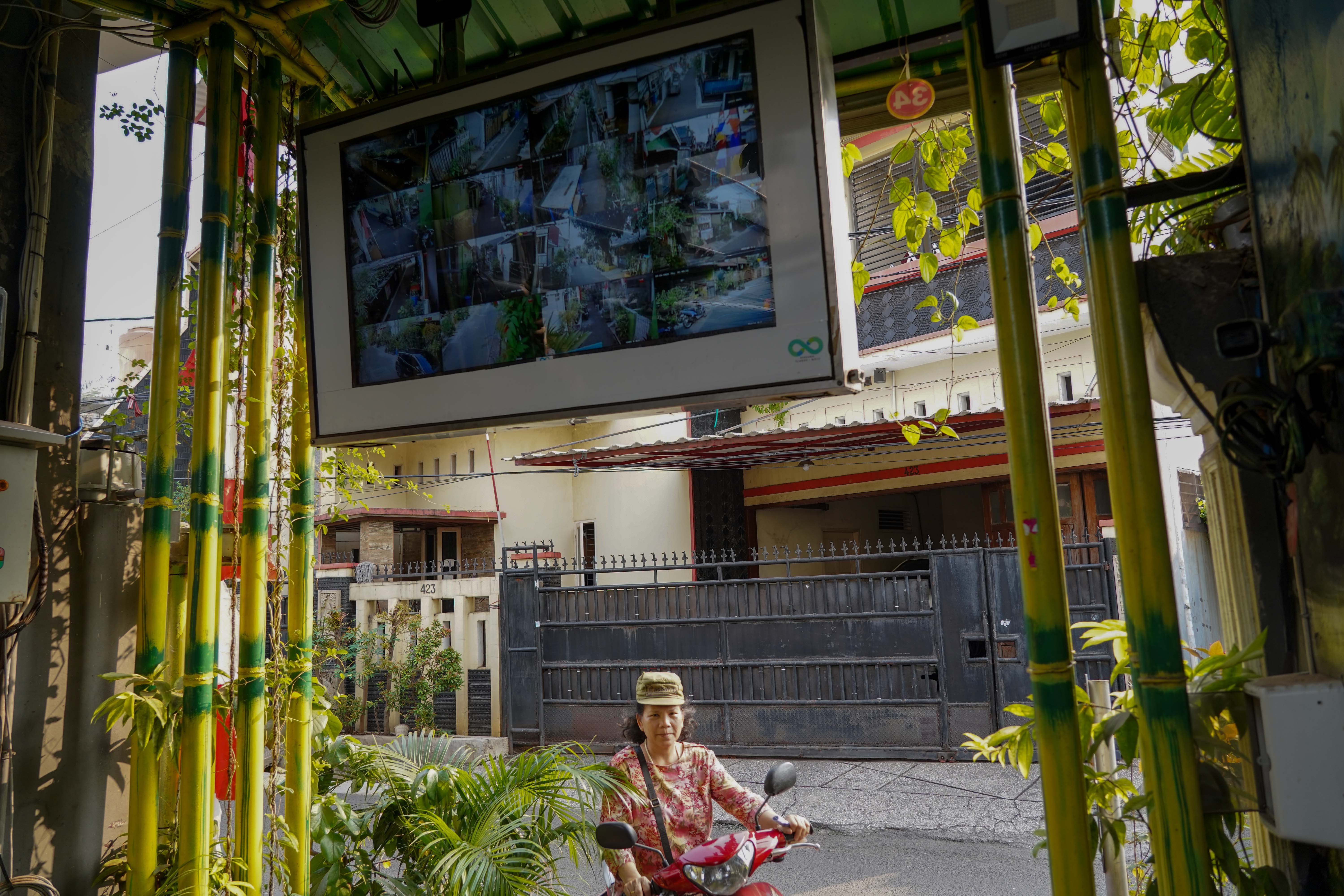 Warga melintas di dekat layar digital yang menunjukkan kamera pengawas yang dipasang di kawasan RT.08/RW.04, Malaka Jaya, Duren Sawit, Jakarta Timur. 