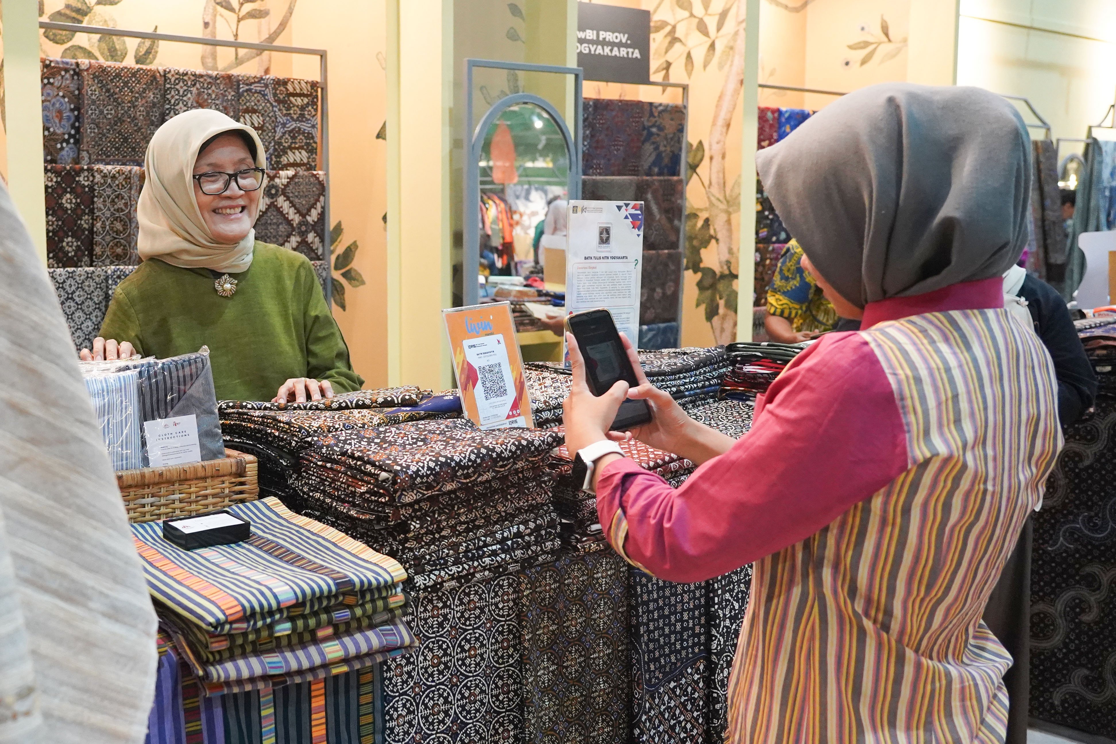 Pengunjung memindai kode batang pembayaran nontunai Quick Response Code Indonesia Standar (QRIS) saat melakukan transaksi pembelian produk pada Pameran Karya Kreatif Indonesia di Jakarta International Convention Center, Kamis (20/8/2026). Bank Indonesia (BI) memperluas MDR QRIS 0% untuk transaksi hingga Rp 100 ribu bagi seluruh kategori merchant yang akan berlaku mulai 1 Oktober 2026.