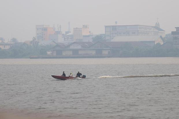 Perahu motor bermuatan penumpang melintasi Sungai Kapuas yang diselimuti kabut asap di Pontianak, Kalimantan Barat, Minggu (23/8/2026). Menurut warga setempat yang menggunakan transportasi sungai, kabut asap akibat kebakaran hutan dan lahan (karhutla) yang menyelimuti wilayah tersebut menyebabkan jarak pandang di kawasan perairan yang sebelumnya luas menjadi terbatas hingga sekitar 20-30 meter.