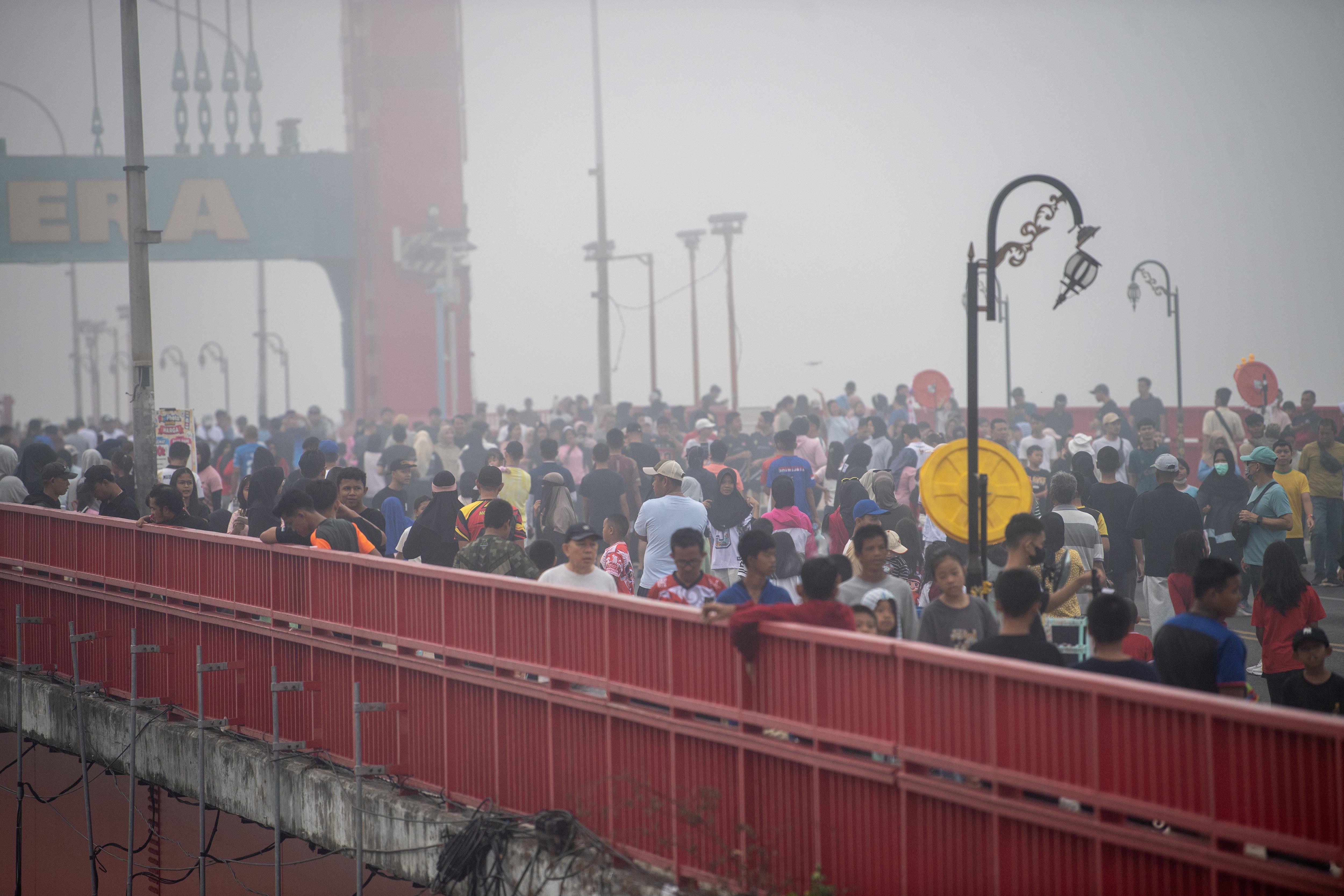 Sejumlah warga berolahraga di atas Jembatan Ampera yang tertutup kabut asap saat pelaksanaan hari bebas kendaraan bermotor di Kota Palembang, Sumatera Selatan, Minggu (23/8/2026). Berdasarkan citra satelit Himawari-9 yang dipantau BMKG pada Minggu (23/8) pukul 10:00 WIB, terdeteksi terjadi sebaran asap di wilayah Sumatera Selatan, Riau, Jambi, Kalimantan Barat, Kalimantan Tengah, Kalimantan Selata, Maluku, Papua Barat, Papua Tengah dan Papua Selatan akibat kebakaran hutan dan lahan.