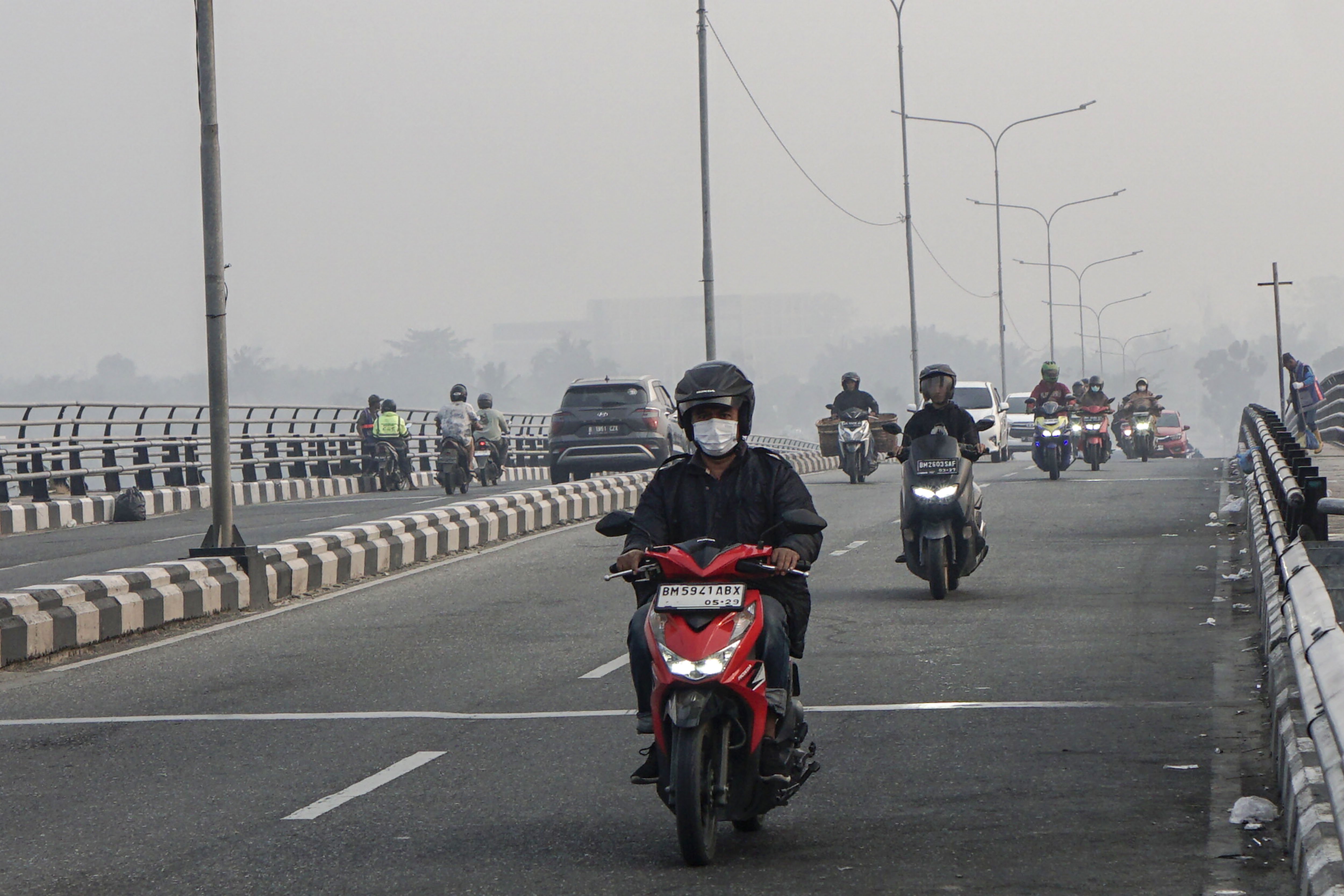Sejumlah pengendara melintas di atas jembatan Siak IV yang dipenuhi kabut asap di Pekanbaru, Riau, Senin (24/8/2026). Pemerintah Provinsi Riau menghimbau kepada masyarakat untuk mengurangi aktivitas di luar ruang serta menggunakan masker kesehatan saat beraktivitas karena memburuknya kualitas udara di Kota Pekanbaru akibat asap dari kebakaran hutan dan lahan. 
