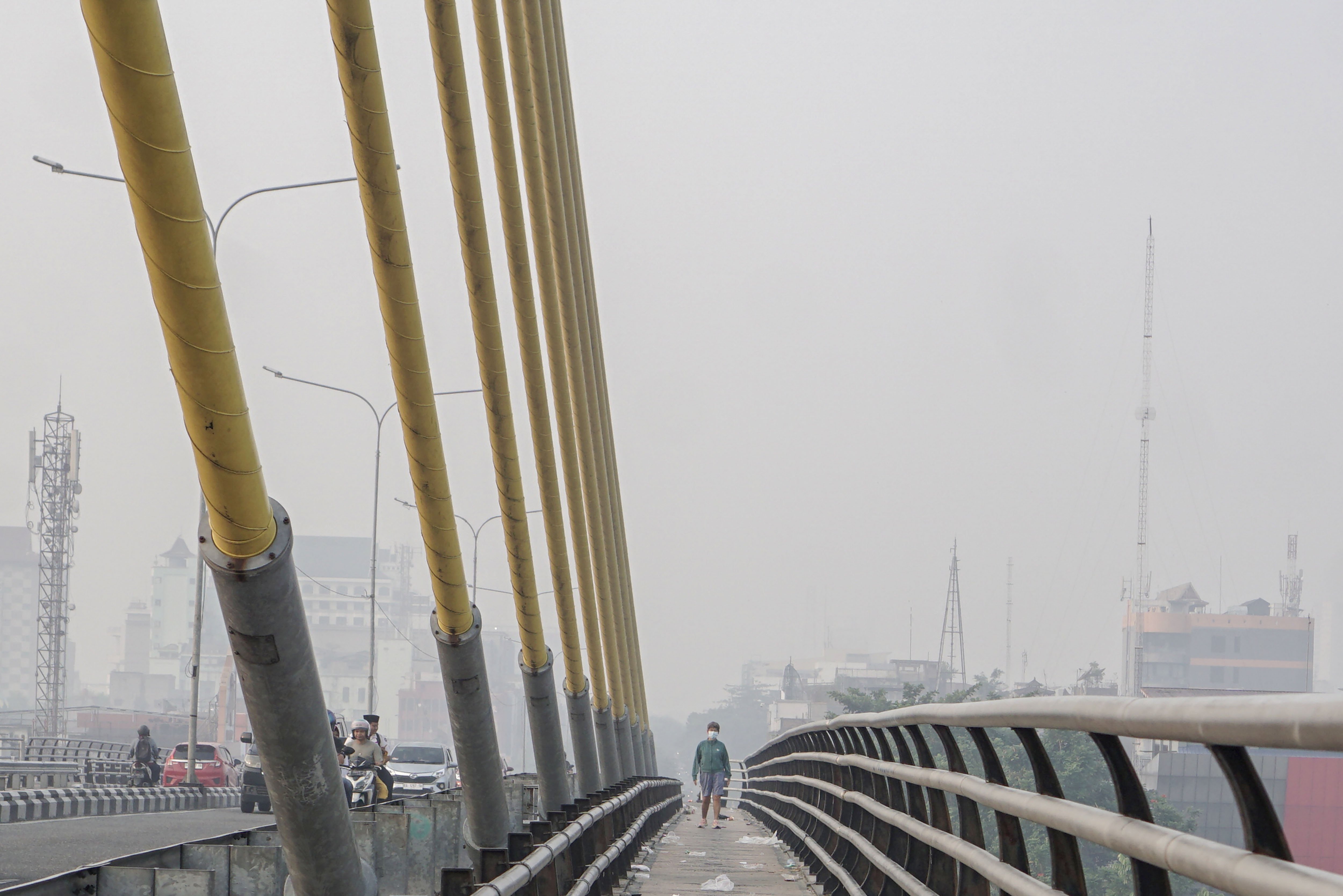 Warga menggunakan masker saat melintas di atas jembatan Siak IV yang dipenuhi kabut asap di Pekanbaru, Riau, Senin (24/8/2026). Pemerintah Provinsi Riau menghimbau kepada masyarakat untuk mengurangi aktivitas di luar ruang serta menggunakan masker kesehatan saat beraktivitas karena memburuknya kualitas udara di Kota Pekanbaru akibat asap dari kebakaran hutan dan lahan. 
