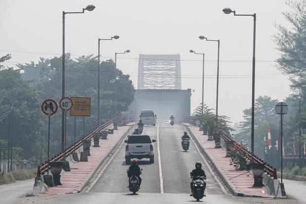 Pengendara melintas di Jembatan Kahayan yang diselimuti asap dampak kebakaran hutan dan lahan di Palangka Raya, Kalimantan Tengah, Jumat (28/8/2026). Berdasarkan data citra satelit Himawari-9 pantauan Badan Meteorologi Klimatologi dan Geofisika (BMKG) pada Jumat 13:00 WIB terdeteksi asap di wilayah Kalimantan Tengah dengan sebaran bergerak ke arah barat laut dan utara.