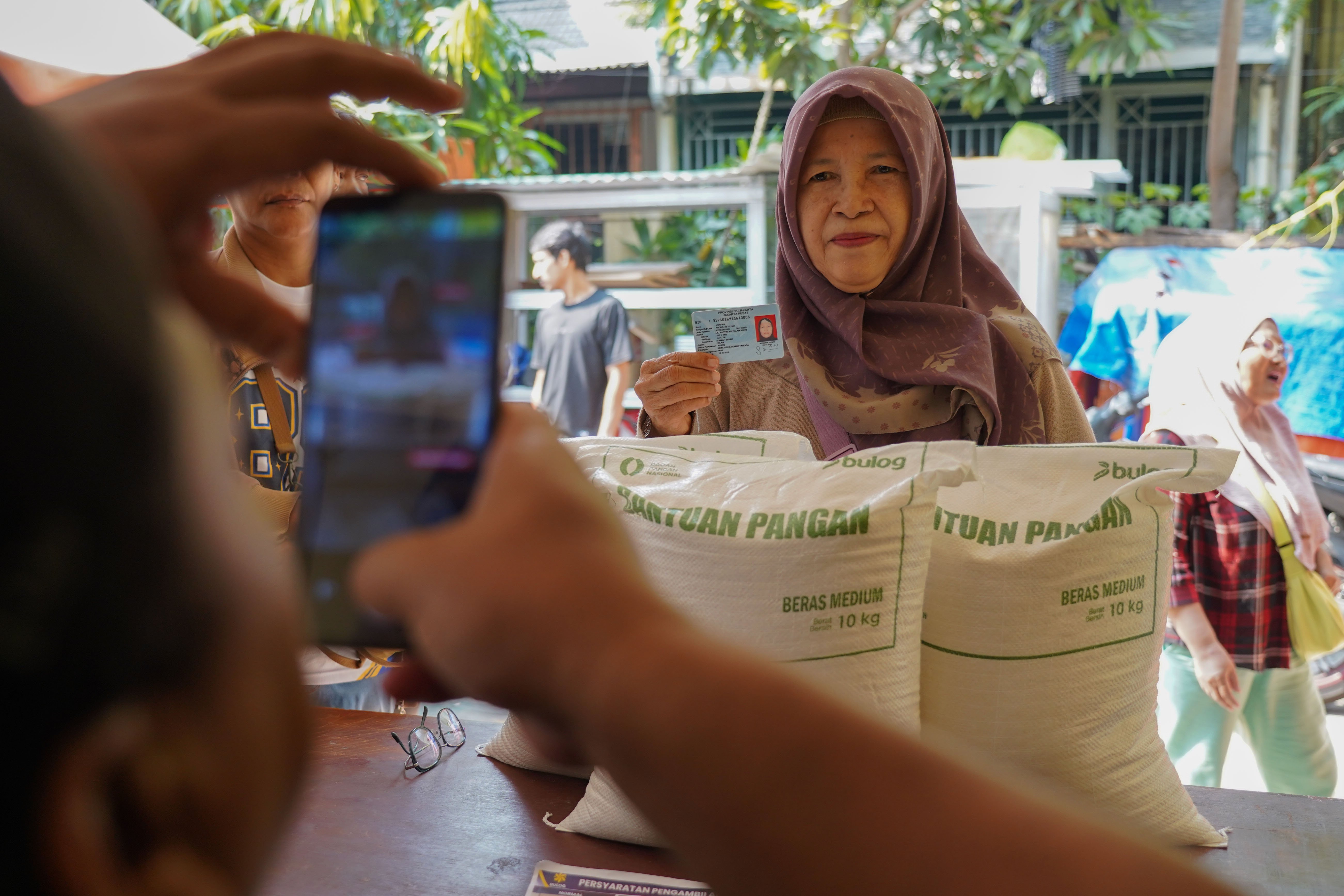 Petugas memotret warga Penerima Bantuan Pangan (PBP) saat penyaluran beras Kelurahan Kartini, Kecamatan Sawah Besar, Jakarta Pusat, Selasa (15/9/2026). Pemerintah memberikan Bantuan Pangan Beras yang menyasar sekitar 33,2 juta keluarga di kategori desil 1 hingga desil 4 dengan skema penyaluran secara rapel untuk alokasi tiga bulan sehingga penerima memperoleh total beras sebanyak 30 kilogram.