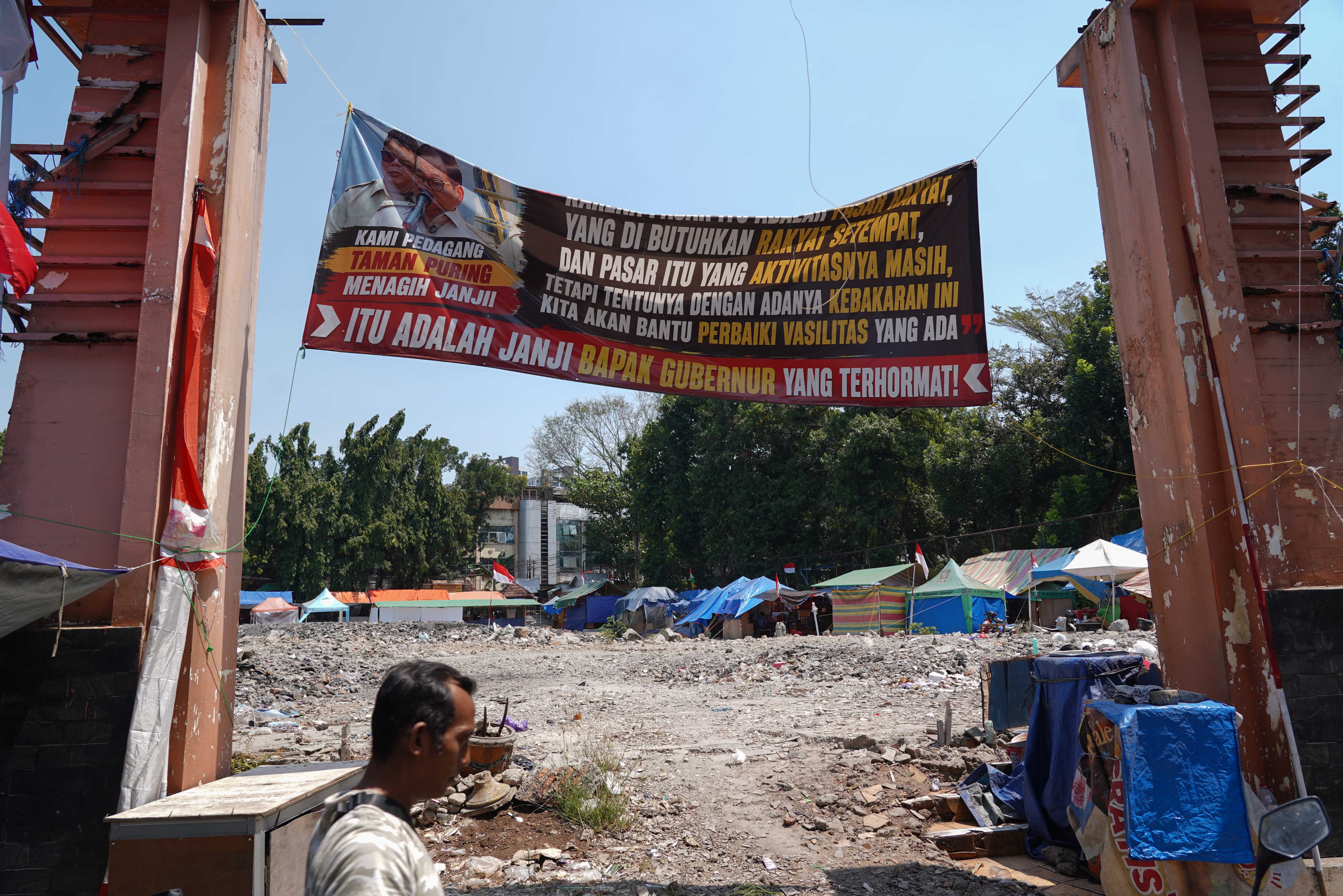 Warga berjalan di dekat puing-puing kios pedagang pascakebakaran di Pasar Taman Puring, Kebayoran Baru, Jakarta Selatan, Senin (14/9/2026). Setahun pascakebakaran yang melanda pasar tersebut pada 28 Juli 2025 dan menghanguskan 512 kios, para pedagang menagih janji Pemerintah Provinsi DKI Jakarta untuk merevitalisasi Pasar Taman Puring agar kegiatan jual beli dapat berlangsung seperti sedia kala.