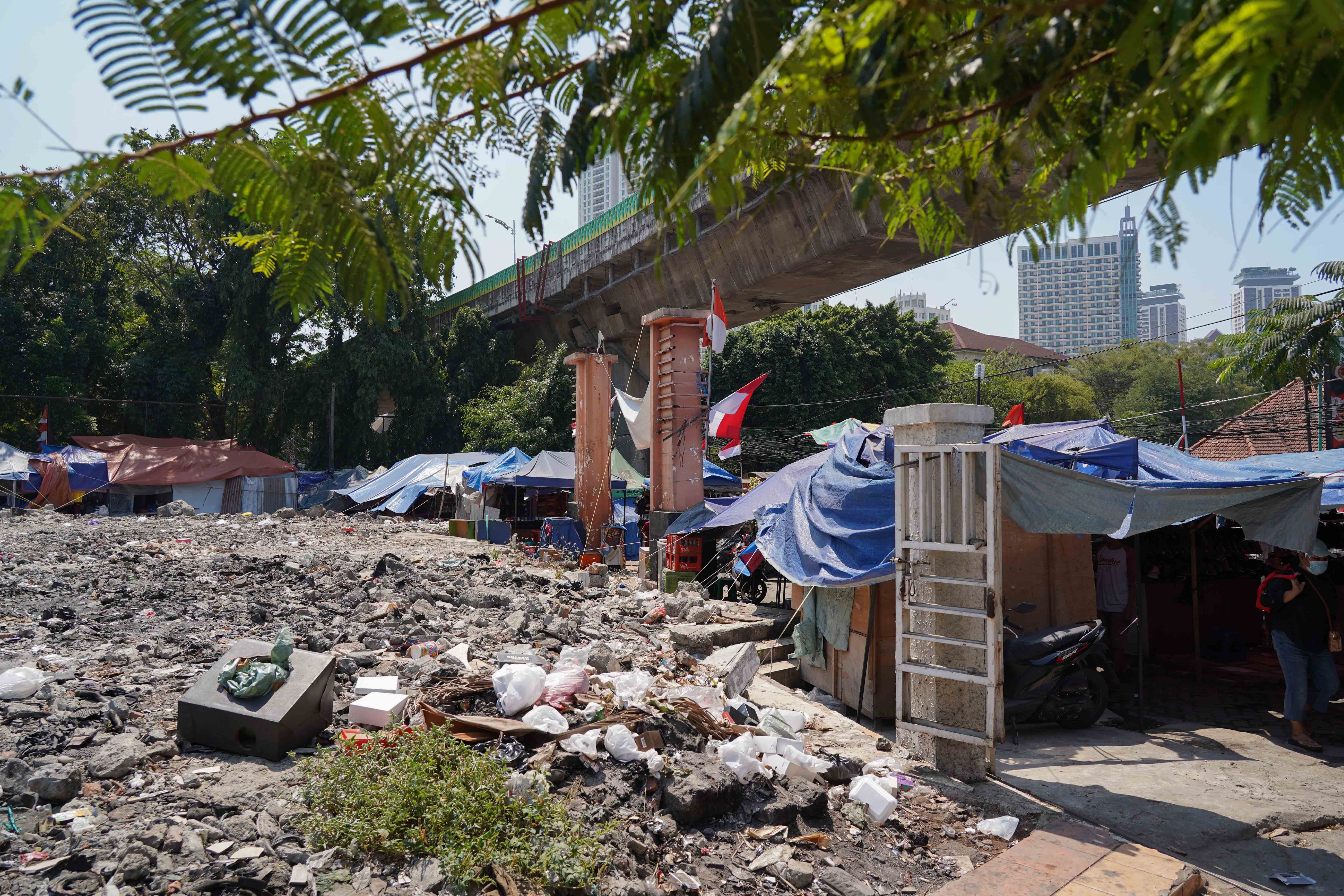 Warga berjalan di dekat puing-puing kios pedagang pascakebakaran di Pasar Taman Puring, Kebayoran Baru, Jakarta Selatan, Senin (14/9/2026). Setahun pascakebakaran yang melanda pasar tersebut pada 28 Juli 2025 dan menghanguskan 512 kios, para pedagang menagih janji Pemerintah Provinsi DKI Jakarta untuk merevitalisasi Pasar Taman Puring agar kegiatan jual beli dapat berlangsung seperti sedia kala.
