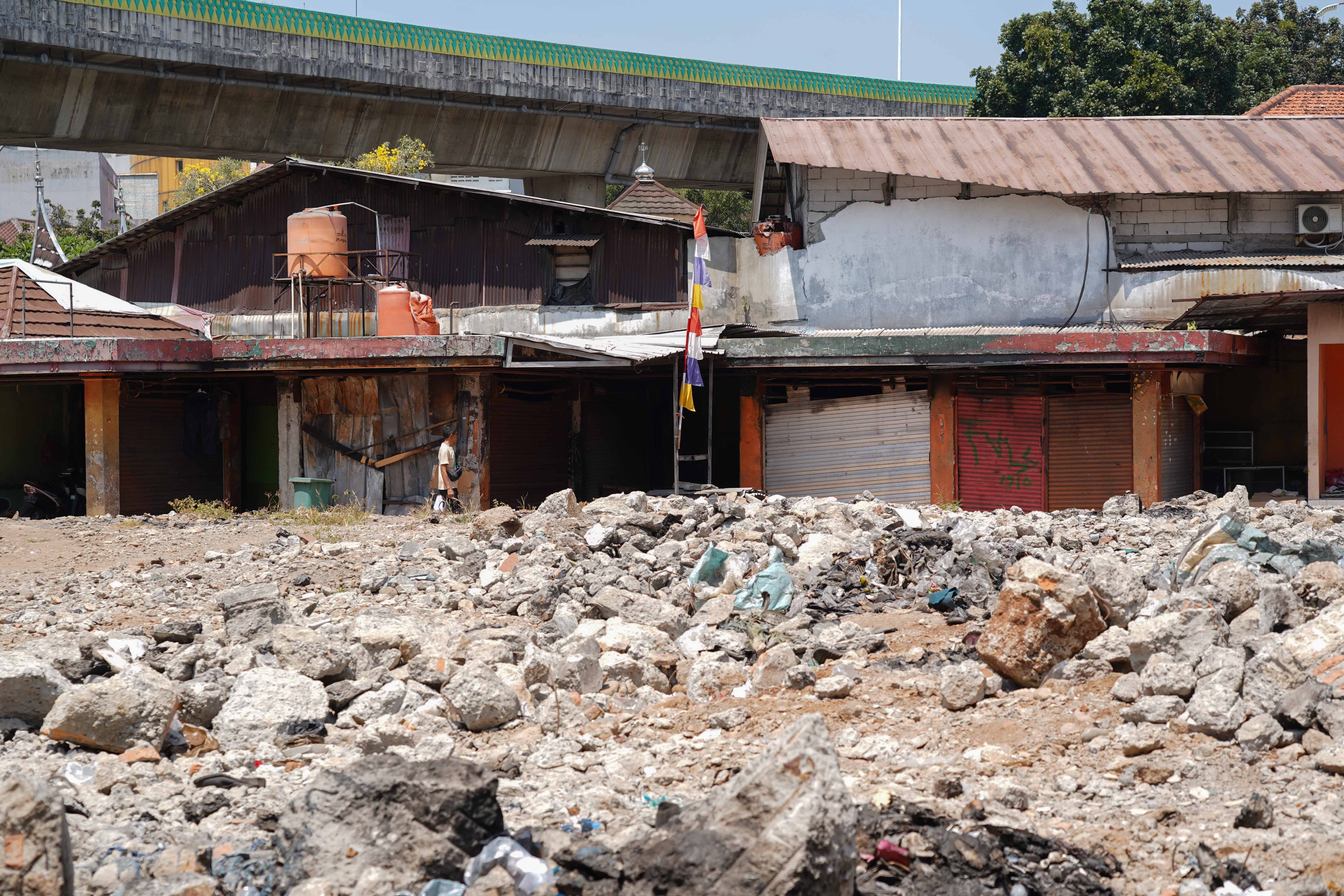Warga berjalan di dekat puing-puing kios pedagang pascakebakaran di Pasar Taman Puring, Kebayoran Baru, Jakarta Selatan, Senin (14/9/2026). Setahun pascakebakaran yang melanda pasar tersebut pada 28 Juli 2025 dan menghanguskan 512 kios, para pedagang menagih janji Pemerintah Provinsi DKI Jakarta untuk merevitalisasi Pasar Taman Puring agar kegiatan jual beli dapat berlangsung seperti sedia kala.