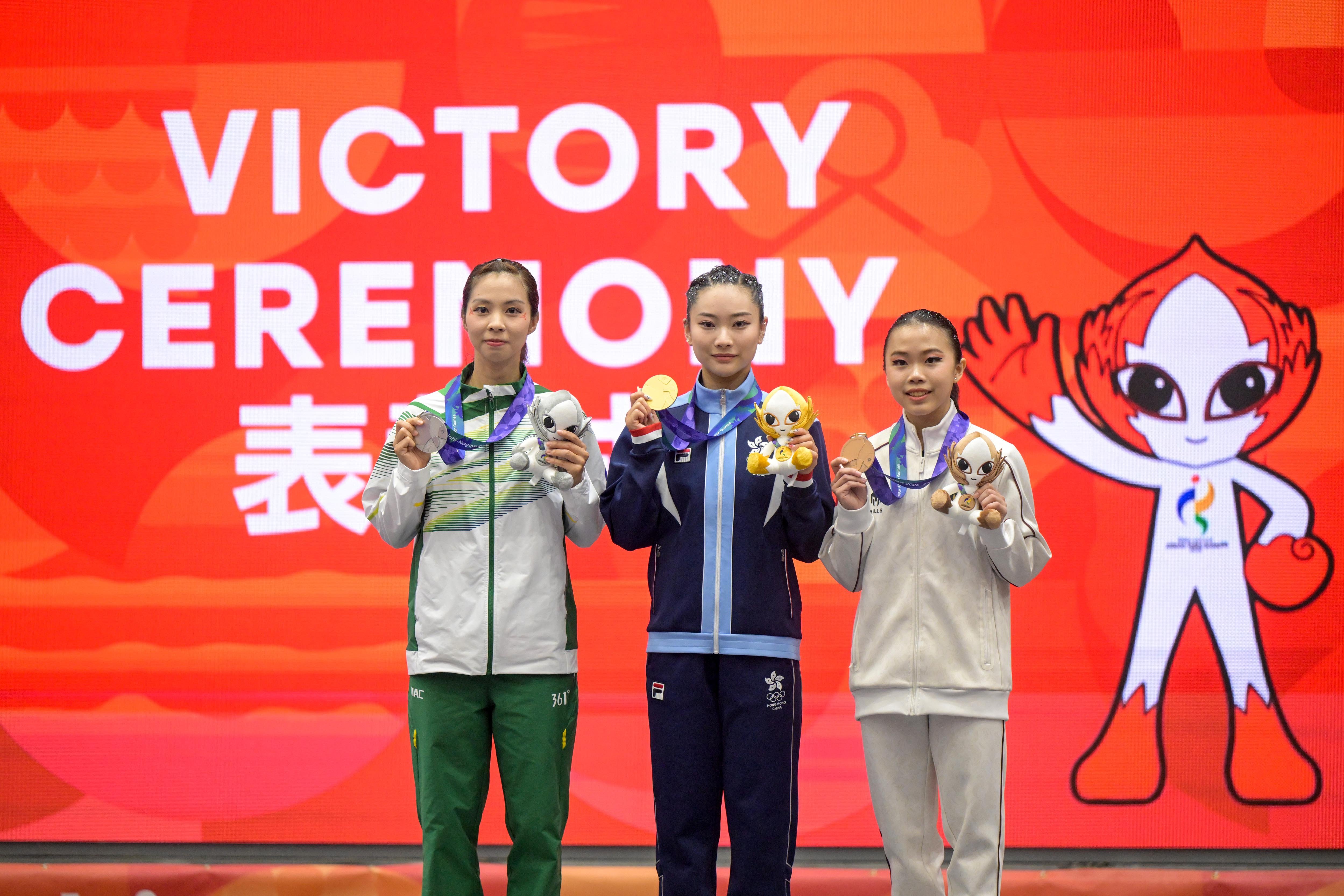 Pewushu Indonesia Eugenia Diva Widodo (kanan), pewushu Hongkong Lydia Sham (tengah), pewushu Makau Sou Cho Man (kiri) berfoto bersama dengan memegang medali wushu nomor taolu changquan putri Asian Games Aichi-Nagoya 2026 di Aichi Prefectural Martial Arts Hall, Aichi, Jepang, Senin (21/9/2026). Eugenia Diva Widodo berhasil meraih medali perunggu dengan skor 9.706, sedangkan medali emas diraih pewushu Hongkong Lydia Sham dengan skor 9.713 dan medali perak oleh pewushu Makau Sou Cho Man dengan skor 9.710.