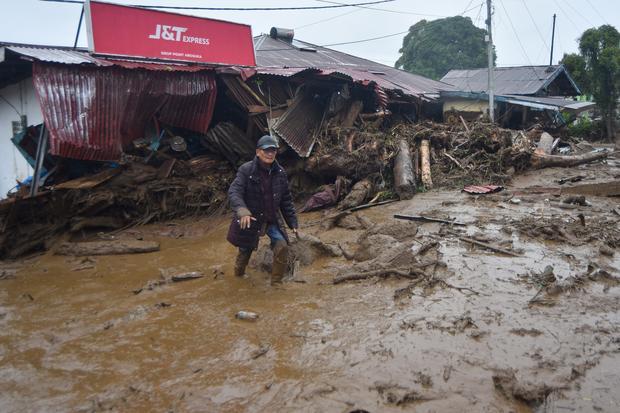 Warga berjalan melewati material banjir bandang di Arosuka, Kabupaten Solok, Sumatera Barat, Selasa (22/9/2026). Banjir bandang yang menerjang kawasan perkantoran di pusat kabupaten pada Senin (21/9) malam itu juga memutus akses jalan nasional dan menyebabkan sejumlah korban hilang.