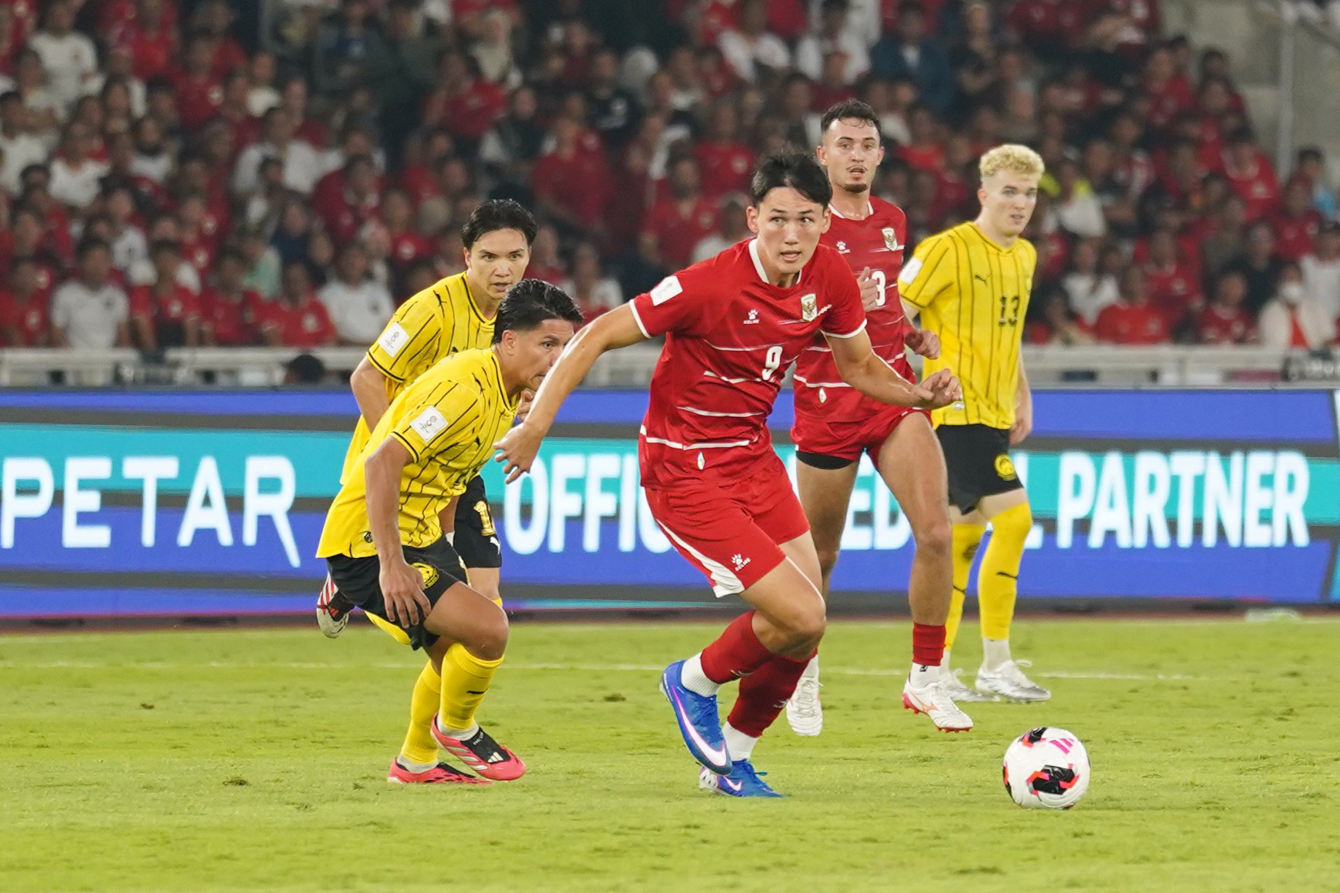 Pesepak bola Timnas Indonesia Mitchell Baker (tengah) membawa bola yang dikawal oleh pesepak bola Timnas Malaysia saat bertanding pada FIFA ASEAN Cup 2026 di Stadion Utama Gelora Bung Karno, Jakarta, Senin (28/9/2026). Pertandingan tersebut berakhir imbang dengan skor 0-0. 