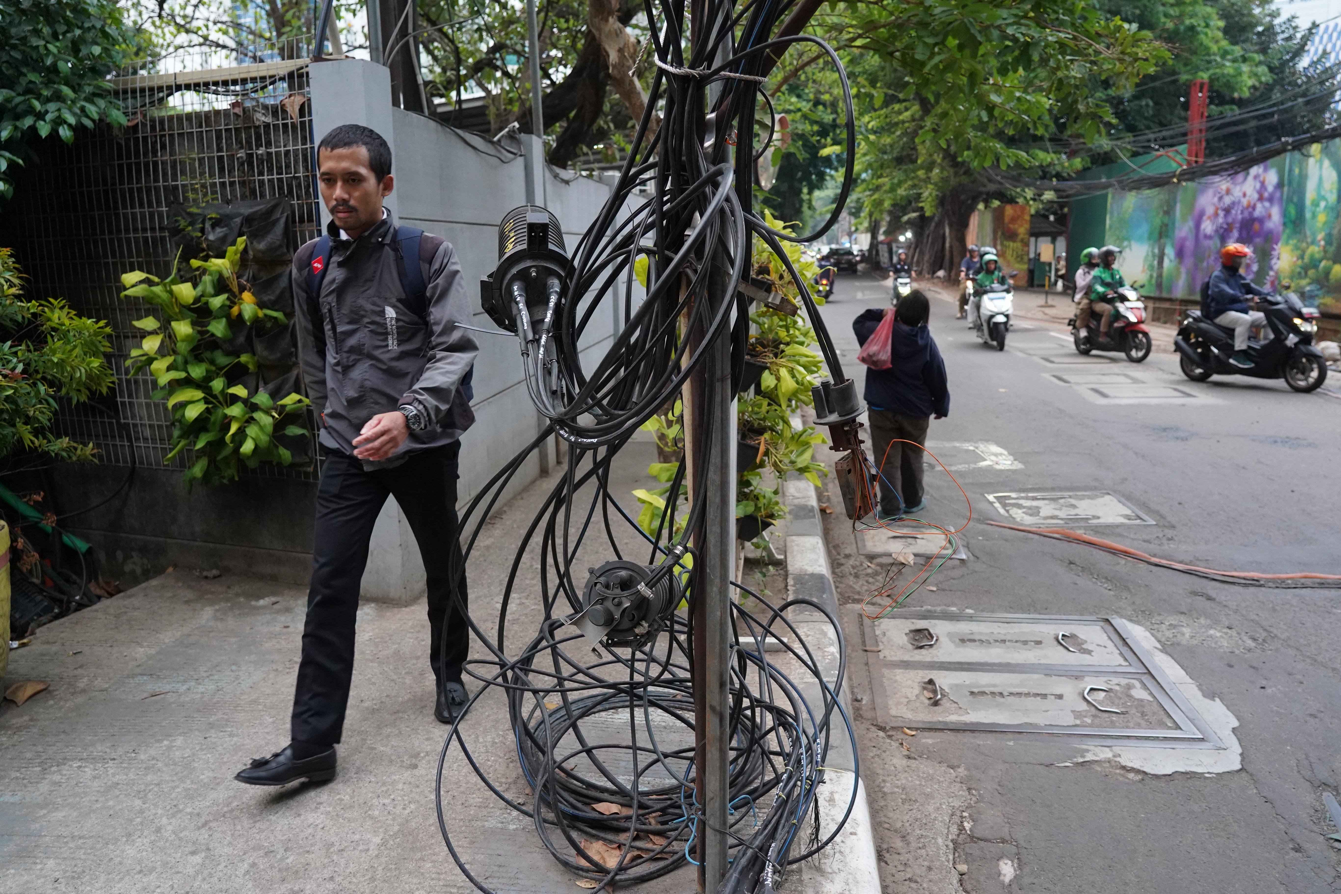 Warga berjalan di dekat kabel yang semrawut di kawasan Jalan Kuningan Barat Raya, Mampang Prapatan, Jakarta Selatan, Rabu (30/9/2026). Pemerintah Provinsi DKI Jakarta menargetkan seluruh kabel udara di Ibu Kota dapat diturunkan ke bawah tanah dalam lima tahun ke depan sebagai upaya memperbaiki wajah kota agar lebih rapi, aman dan nyaman bagi masyarakat.