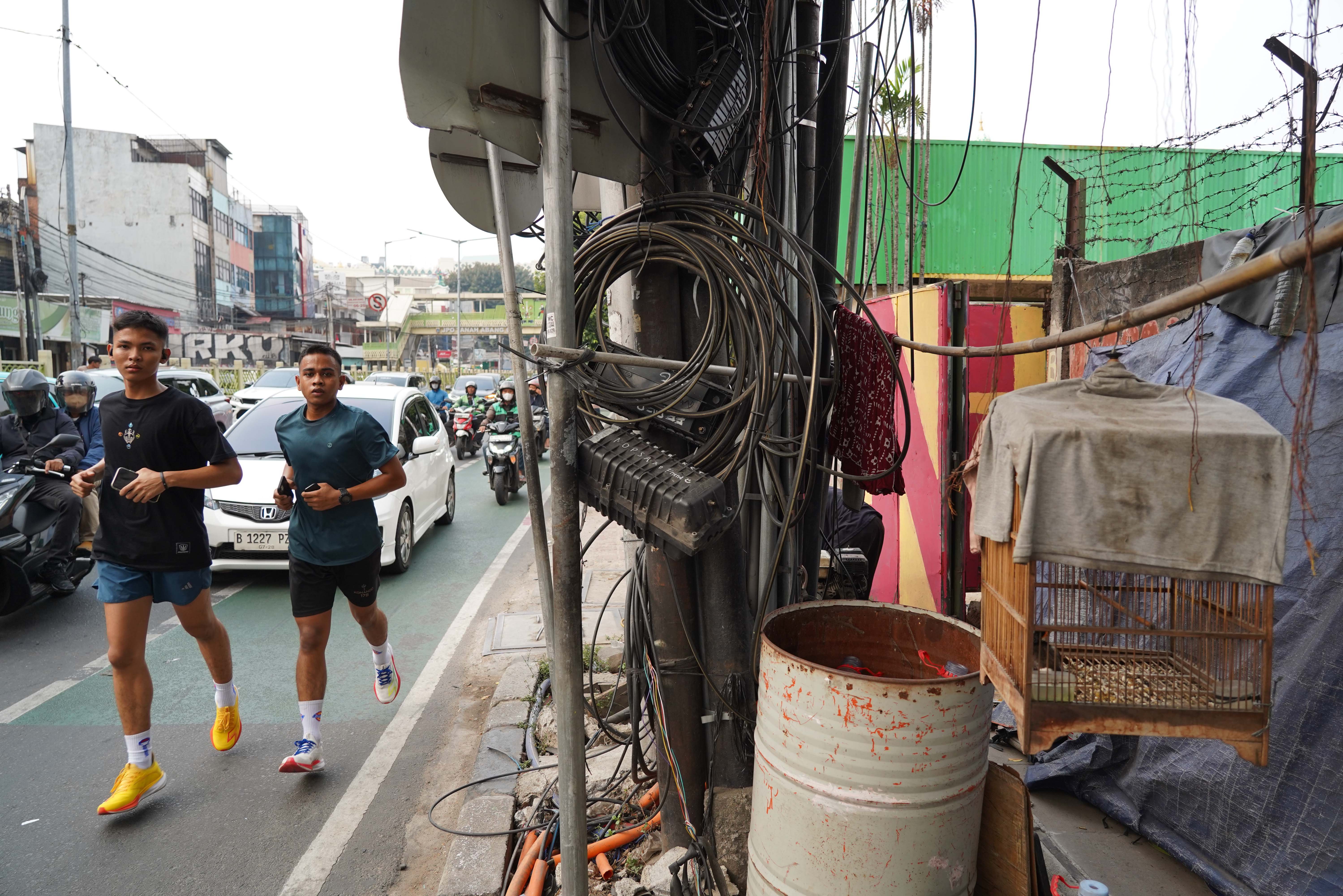 Warga melintas di dekat kabel yang semrawut di kawasan Jalan K.H. Mas Mansyur, Tanah Abang, Jakarta Pusat, Rabu (30/9/2026). Pemerintah Provinsi DKI Jakarta menargetkan seluruh kabel udara di Ibu Kota dapat diturunkan ke bawah tanah dalam lima tahun ke depan sebagai upaya memperbaiki wajah kota agar lebih rapi, aman dan nyaman bagi masyarakat.
