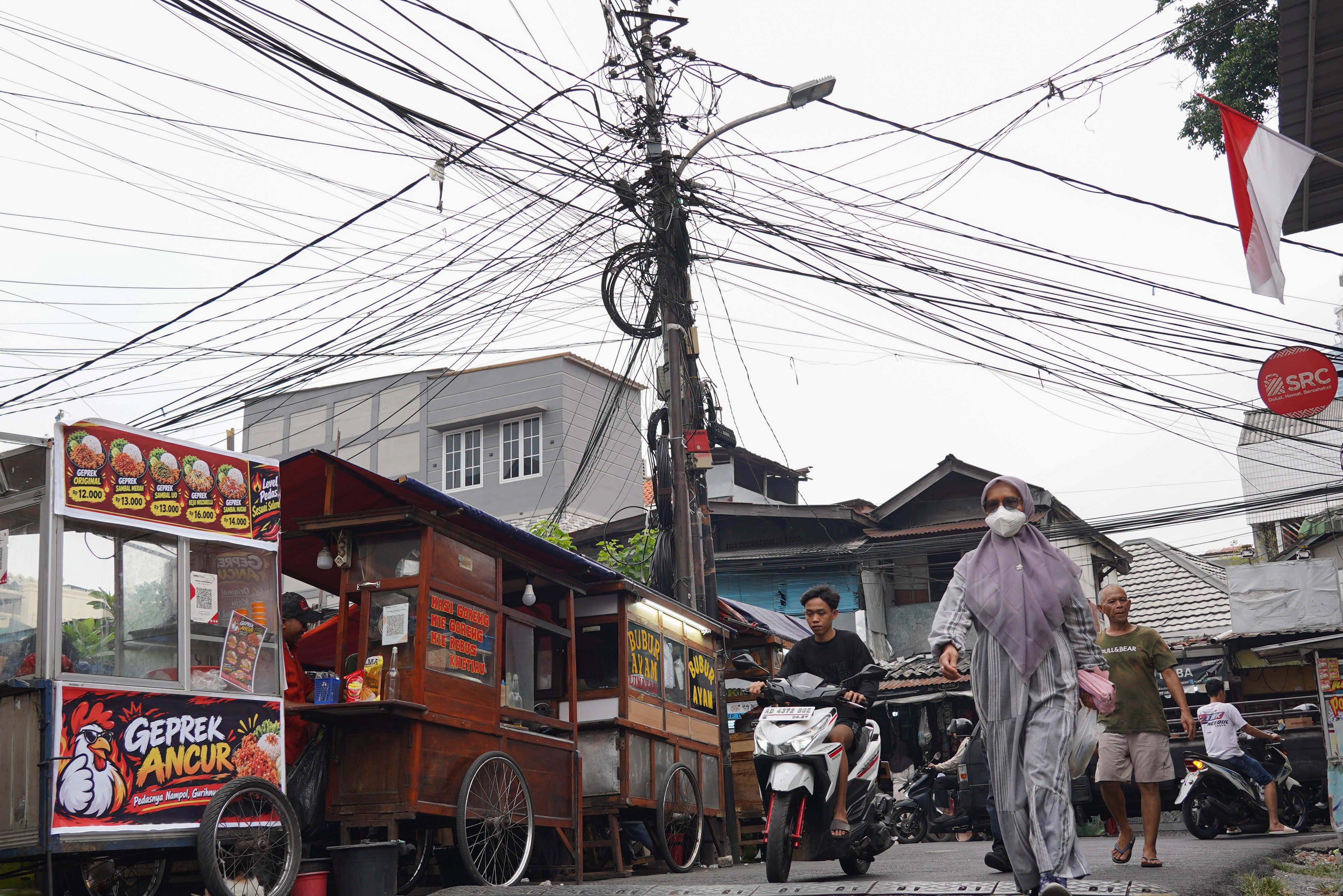 Warga melintas di dekat kabel yang semrawut di kawasan Jalan Lontar Raya, Kebon Kacang, Tanah Abang, Jakarta Pusat, Rabu (30/9/2026). Pemerintah Provinsi DKI Jakarta menargetkan seluruh kabel udara di Ibu Kota dapat diturunkan ke bawah tanah dalam lima tahun ke depan sebagai upaya memperbaiki wajah kota agar lebih rapi, aman dan nyaman bagi masyarakat.