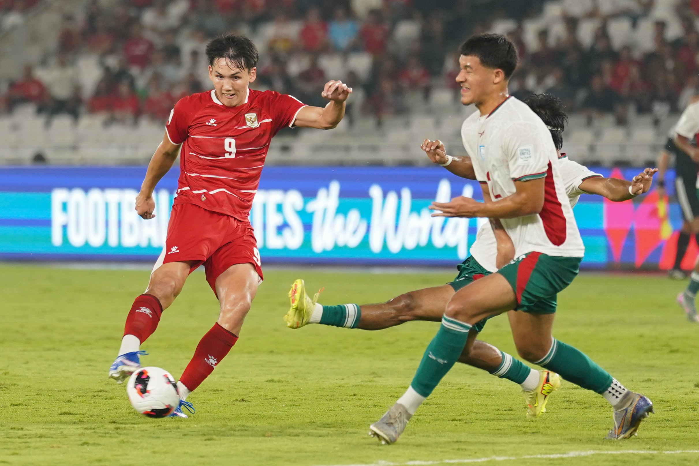 Pesepak bola Timnas Indonesia Mitchell Baker (kiri) menendang bola yang dihalau oleh pesepak bola Timnas Bangladesh saat bertanding pada FIFA ASEAN Cup 2026 di Stadion Utama Gelora Bung Karno, Jakarta, Kamis (1/10/2026). Pertandingan tersebut dimenangkan oleh Timnas Indonesia dengan skor 9-2 dan memastikan skuad asuhan pelatih John Herdman melaju ke babak final.