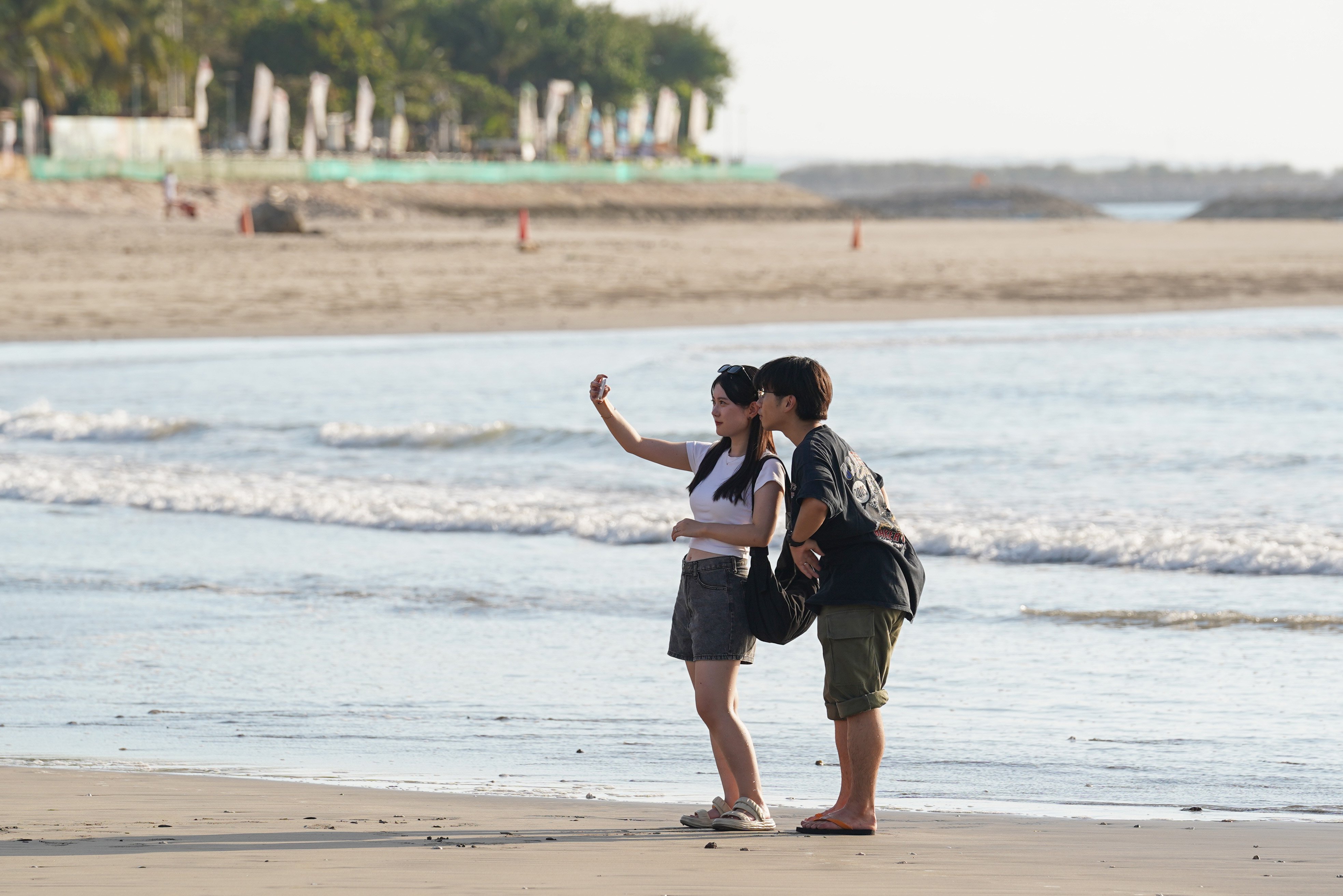 Wisatawan berfoto saat berkunjung ke Pantai Kuta di Kabupaten Badung, Bali, Kamis (8/10/2026). Pantai yang memiliki luas sekitar 2,5 kilometer ini dikenal sebagai salah satu destinasi wisata di Pulau Dewata yang menawarkan pesona keindahan mulai dari hamparan pasir putih, ombak yang ideal untuk berselancar hingga pemandangan sunset yang memukau.