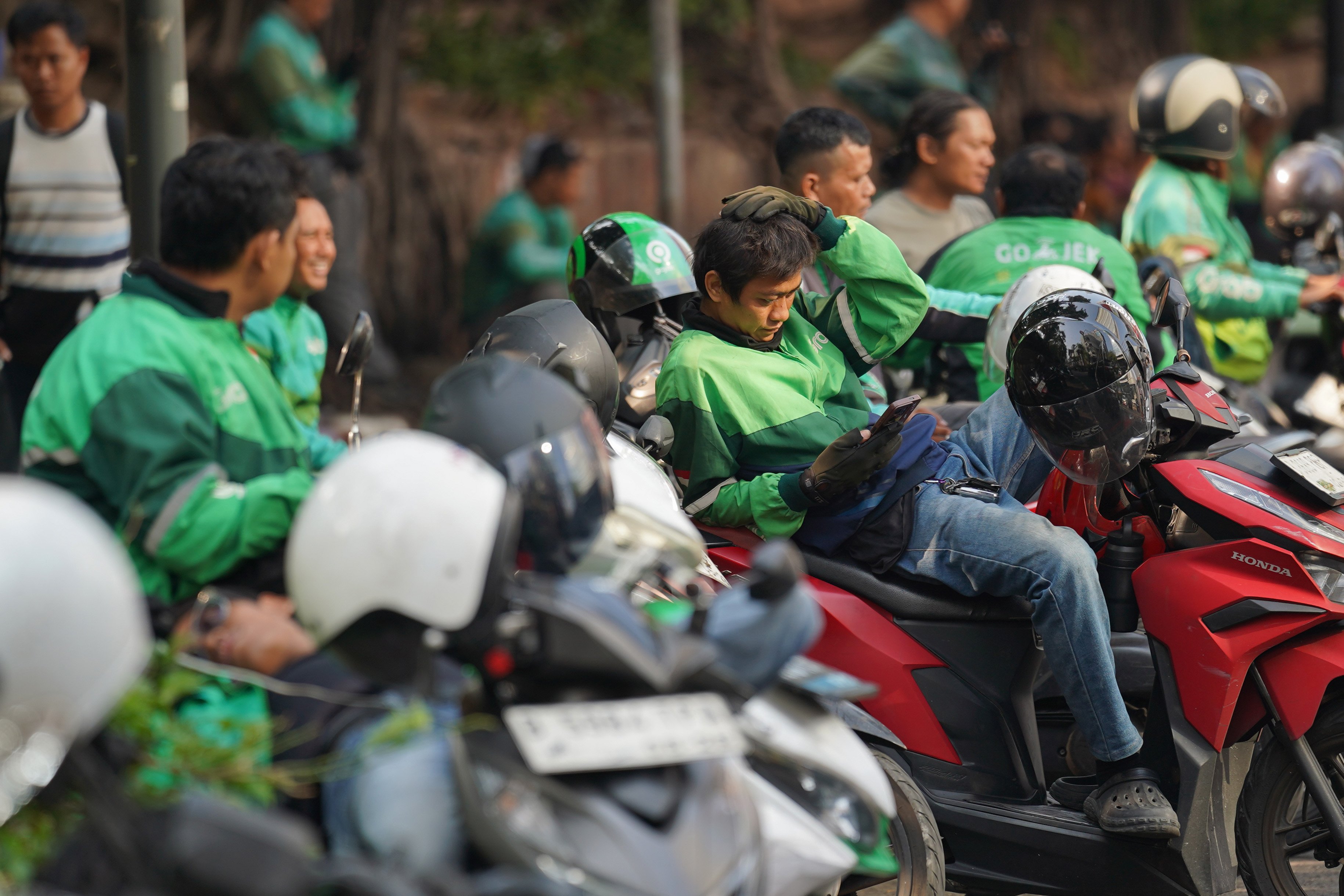Pengemudi ojek online atau ojol menunggu pesanan di kawasan Dukuh Atas, Jakarta, Selasa (13/10/2026). Pemerintah resmi merilis Peraturan Presiden Nomor 27 Tahun 2026 tentang Perlindungan Ekosistem Transportasi Berbasis Platform Digital atau Perpres Ojol yang berisi tentang berbagai aspek terkait transportasi digital, mulai dari sistem elektronik, kemitraan, jaminan sosial, ketenagakerjaan, serta aturan-aturan untuk penerbitan peraturan pelaksanaan.