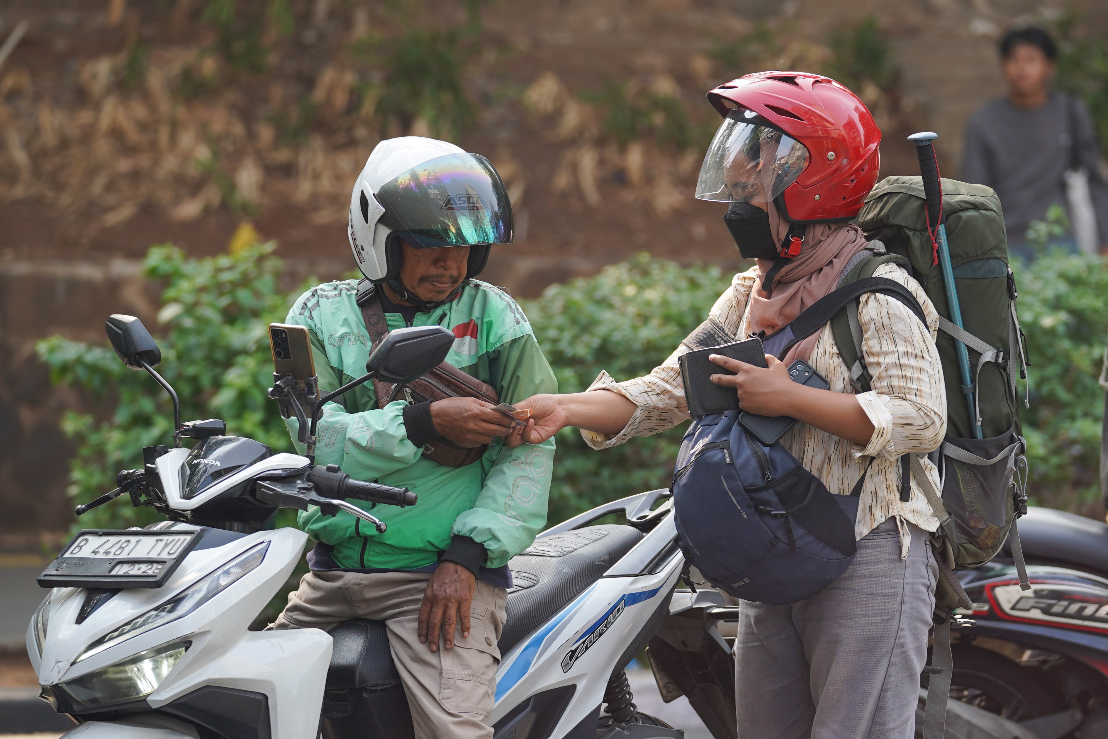 Pengemudi ojek online atau ojol mengantarkan penumpang di kawasan Dukuh Atas, Jakarta, Selasa (13/10/2026). Pemerintah resmi merilis Peraturan Presiden Nomor 27 Tahun 2026 tentang Perlindungan Ekosistem Transportasi Berbasis Platform Digital atau Perpres Ojol yang berisi tentang berbagai aspek terkait transportasi digital, mulai dari sistem elektronik, kemitraan, jaminan sosial, ketenagakerjaan, serta aturan-aturan untuk penerbitan peraturan pelaksanaan.