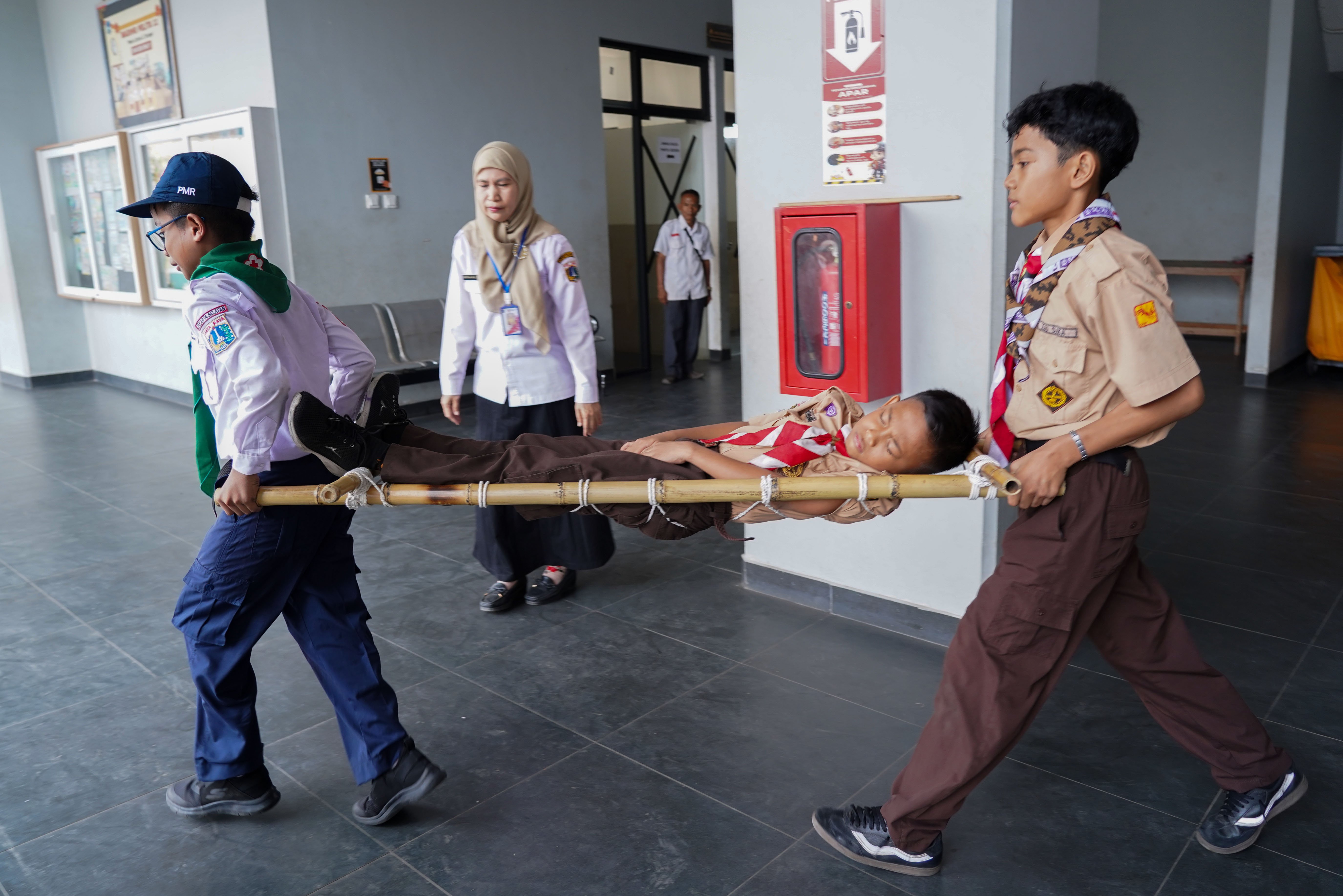 Siswa menandu temannya saat mengikuti simulasi gempa bumi di SDN Pejaten Timur 11, Jakarta, Rabu (21/10/26). Pemerintah Provinsi DKI Jakarta menggelar simulasi gempa bumi serentak pada 21 Oktober 2026 di gedung perkantoran pemerintah, kantor kecamatan dan kelurahan hingga sekolah dalam rangka meningkatkan kesiapsiagaan menghadapi potensi bencana gempa bumi.