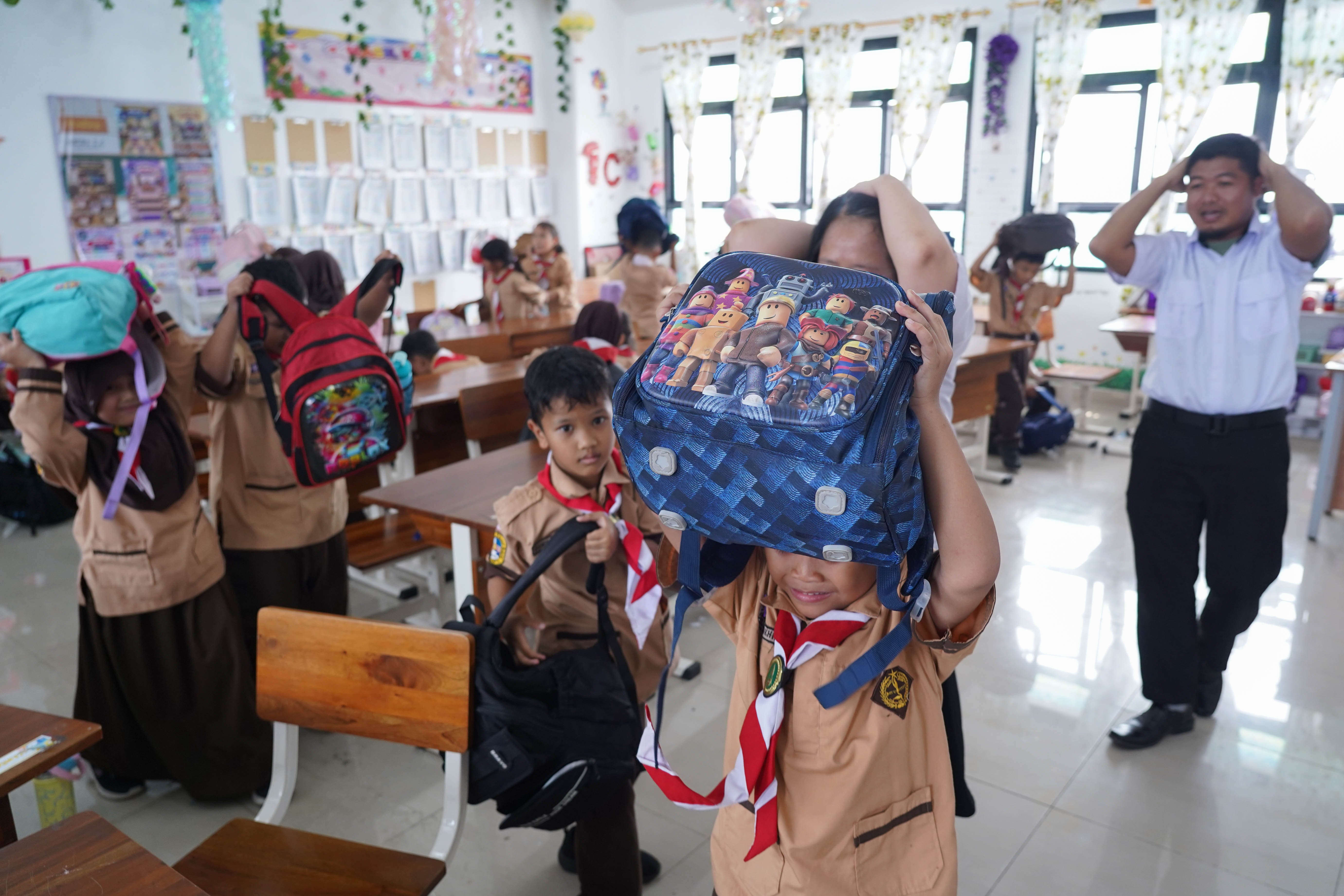 Guru dan siswa berlari menuju lapangan saat mengikuti simulasi gempa bumi di SDN Pejaten Timur 11, Jakarta, Rabu (21/10/26). Pemerintah Provinsi DKI Jakarta menggelar simulasi gempa bumi serentak pada 21 Oktober 2026 di gedung perkantoran pemerintah, kantor kecamatan dan kelurahan hingga sekolah dalam rangka meningkatkan kesiapsiagaan menghadapi potensi bencana gempa bumi.