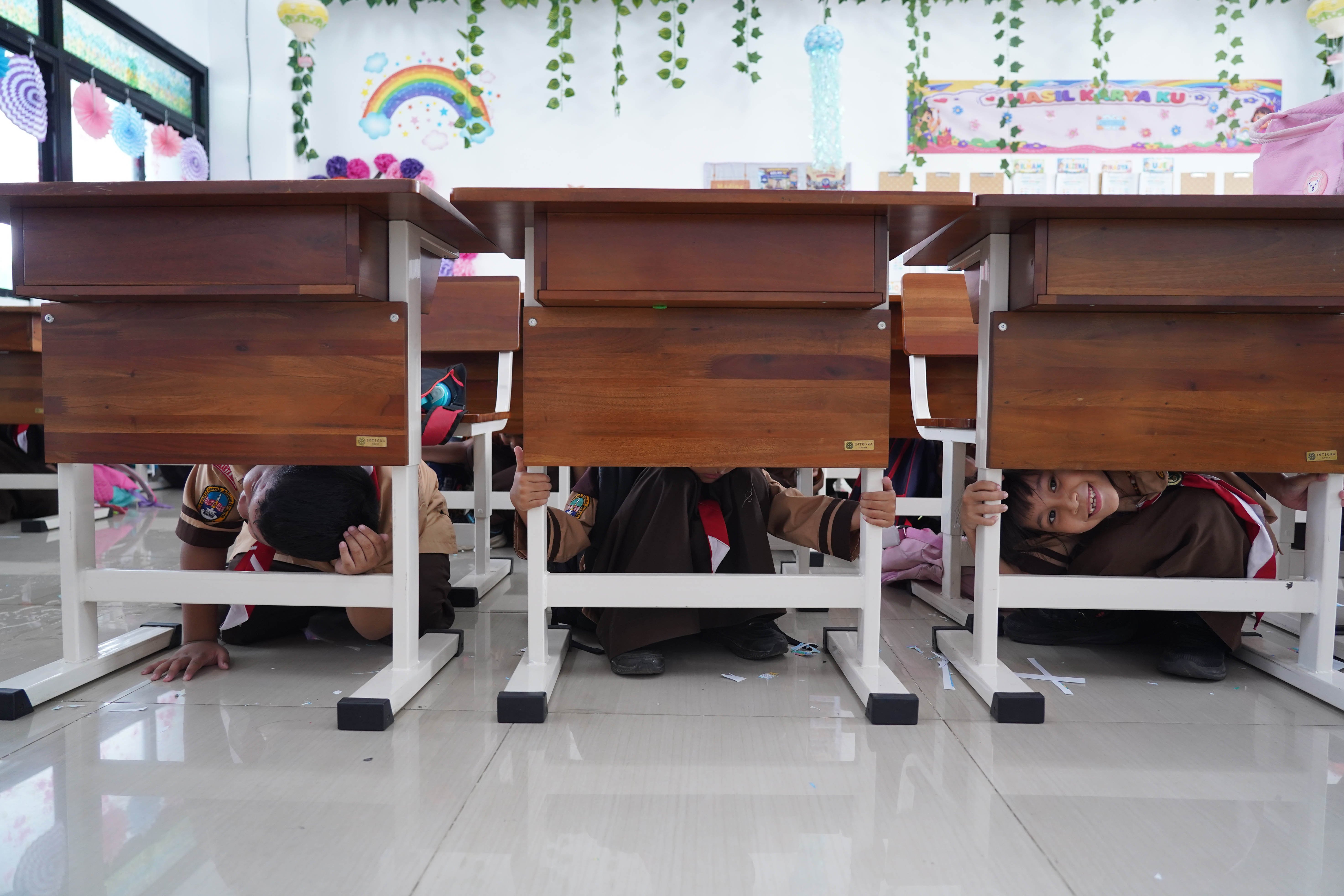 Siswa berlindung di bawah meja saat mengikuti simulasi gempa bumi di SDN Pejaten Timur 11, Jakarta, Rabu (21/10/26). Pemerintah Provinsi DKI Jakarta menggelar simulasi gempa bumi serentak pada 21 Oktober 2026 di gedung perkantoran pemerintah, kantor kecamatan dan kelurahan hingga sekolah dalam rangka meningkatkan kesiapsiagaan menghadapi potensi bencana gempa bumi.