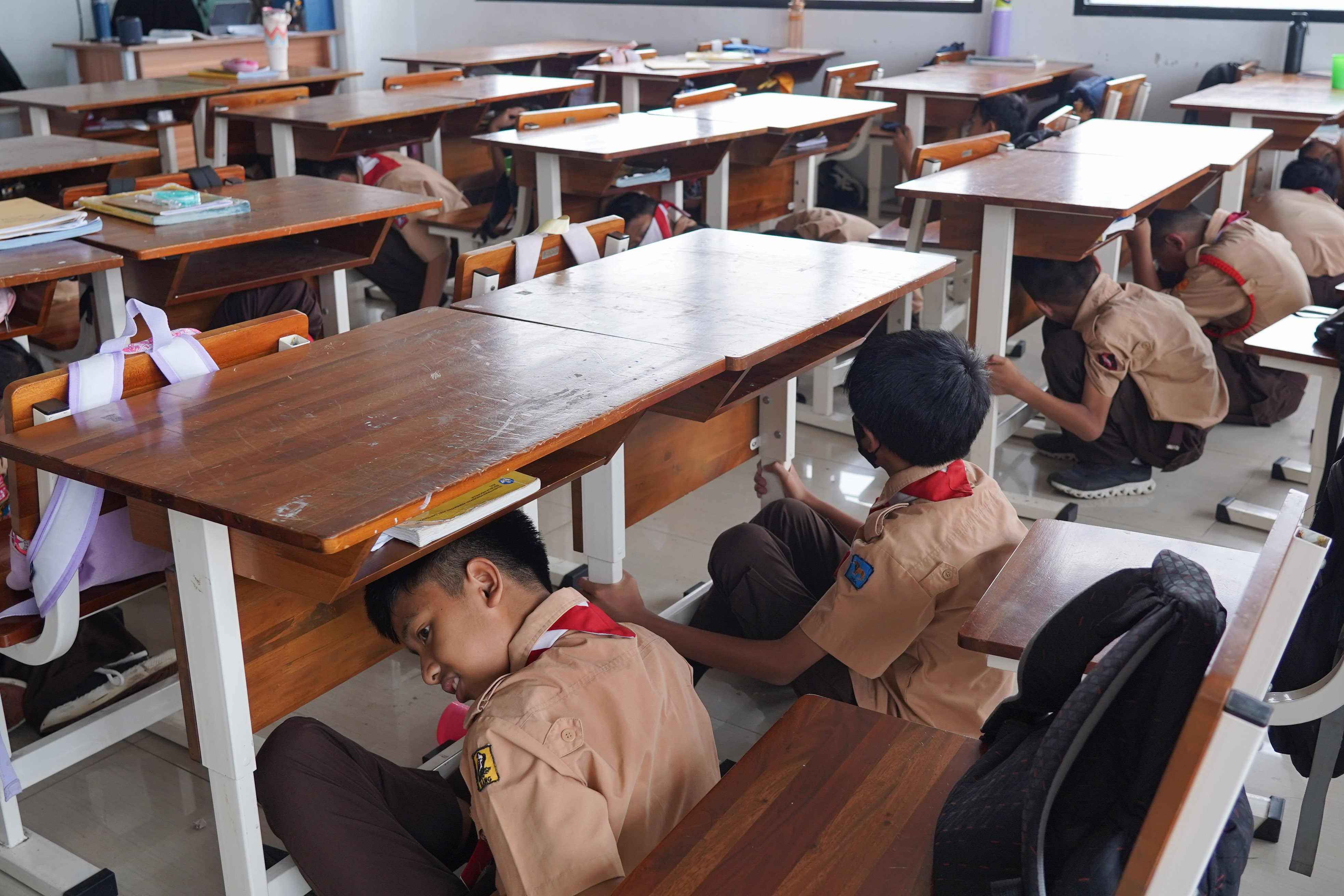 Siswa berlindung di bawah meja saat mengikuti simulasi gempa bumi di SDN Pejaten Timur 11, Jakarta, Rabu (21/10/26). Pemerintah Provinsi DKI Jakarta menggelar simulasi gempa bumi serentak pada 21 Oktober 2026 di gedung perkantoran pemerintah, kantor kecamatan dan kelurahan hingga sekolah dalam rangka meningkatkan kesiapsiagaan menghadapi potensi bencana gempa bumi.