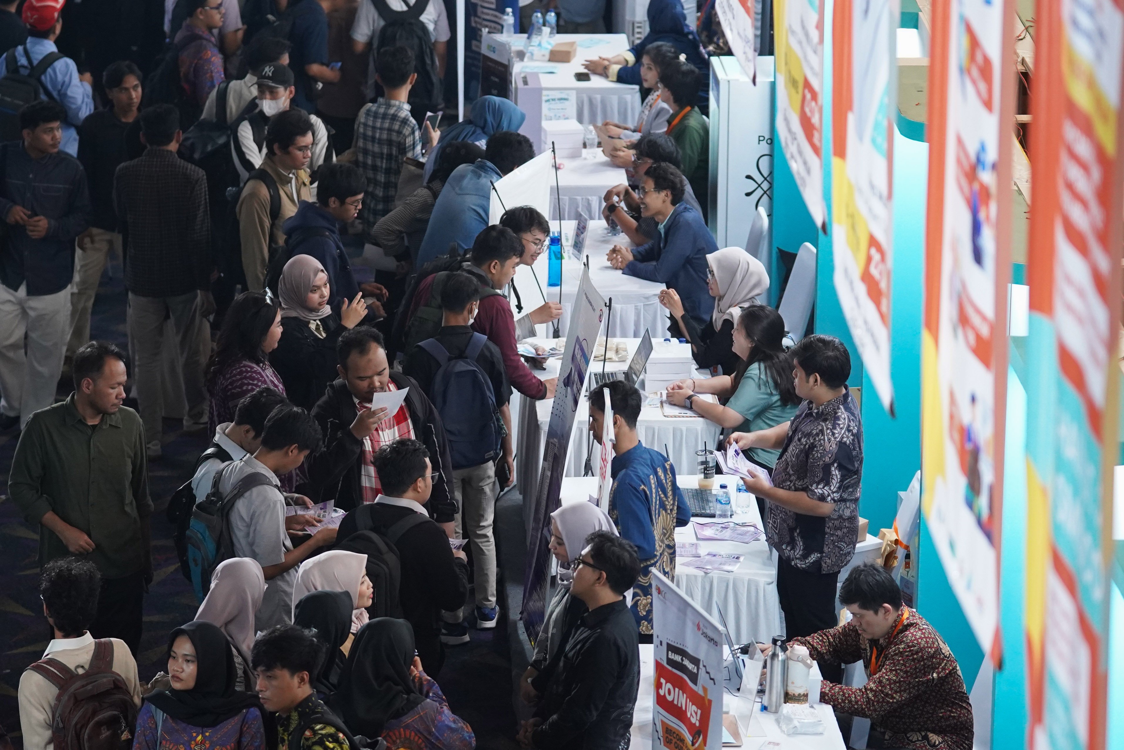 Pencari kerja melihat informasi lowongan kerja yang tersedia saat berlangsungnya bursa kerja di Convention Hall SMESCO, Pancoran, Jakarta, Kamis (22/10/2026). Bursa kerja yang menghadirkan 65 perusahaan dengan peluang kerja dalam negeri dan 10 perusahaan dengan peluang kerja luar negeri ini digelar pada 22-23 Oktober 2026.