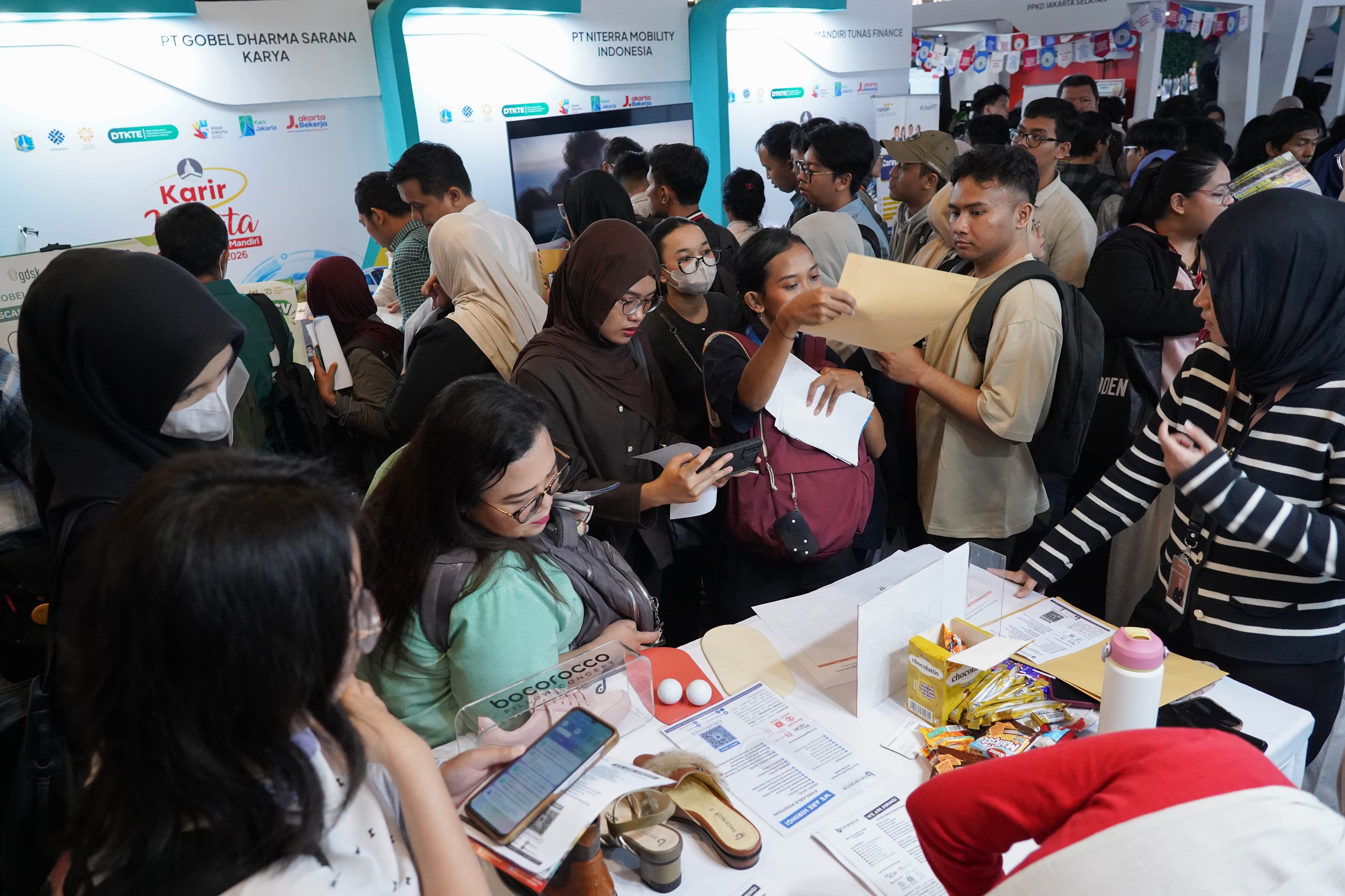 Pencari kerja melihat informasi lowongan kerja yang tersedia saat berlangsungnya bursa kerja di Convention Hall SMESCO, Pancoran, Jakarta, Kamis (22/10/2026). Bursa kerja yang menghadirkan 65 perusahaan dengan peluang kerja dalam negeri dan 10 perusahaan dengan peluang kerja luar negeri ini digelar pada 22-23 Oktober 2026.